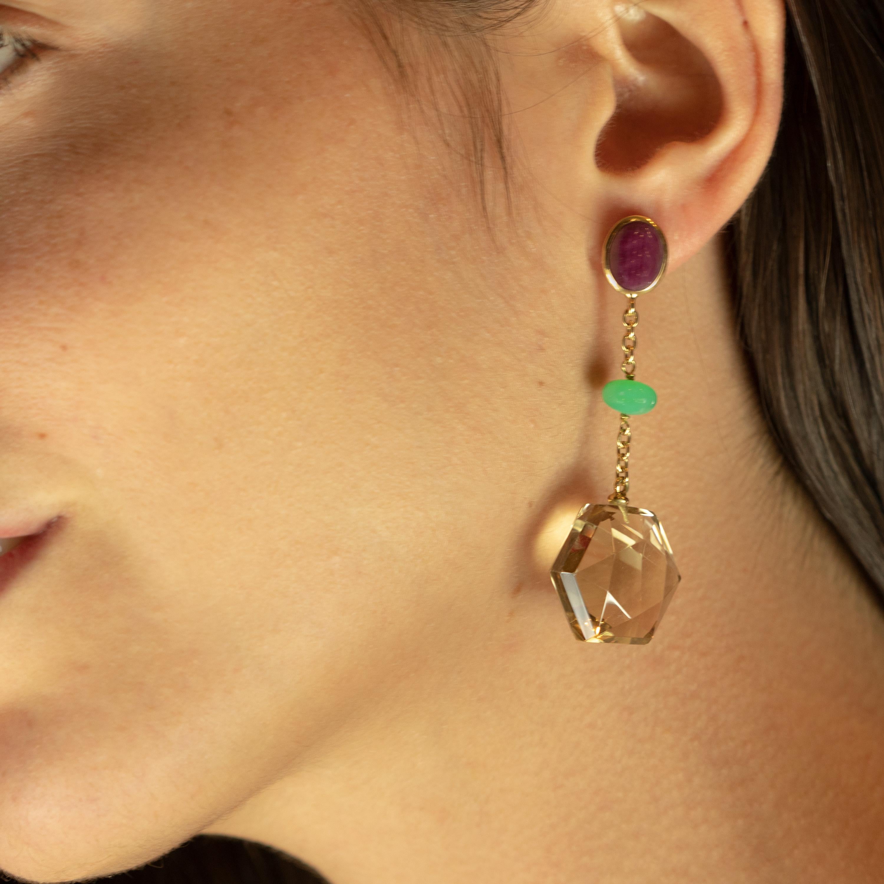 Design geometrico e colorato pieno di vita. Un rubino ovale e viola scuro, un crisofraso rotondo e un esagono di quarzo citrino, che innovano in un design irregolare e molto moderno. Uniti da una delicata catena in oro giallo 18 carati che unisce