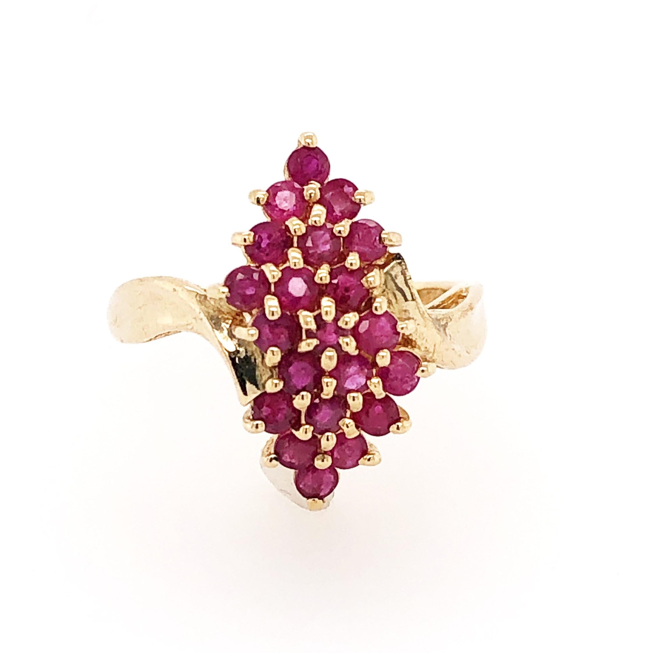 A cascade of pleasingly pink rubies adorn this gorgeous fourteen carat yellow gold cocktail ring. Twenty one prong set round ruby gemstones, .21 carats total weight, create the 7/8 inch long head held by a twist of gold . In size 8. In gift box. 
