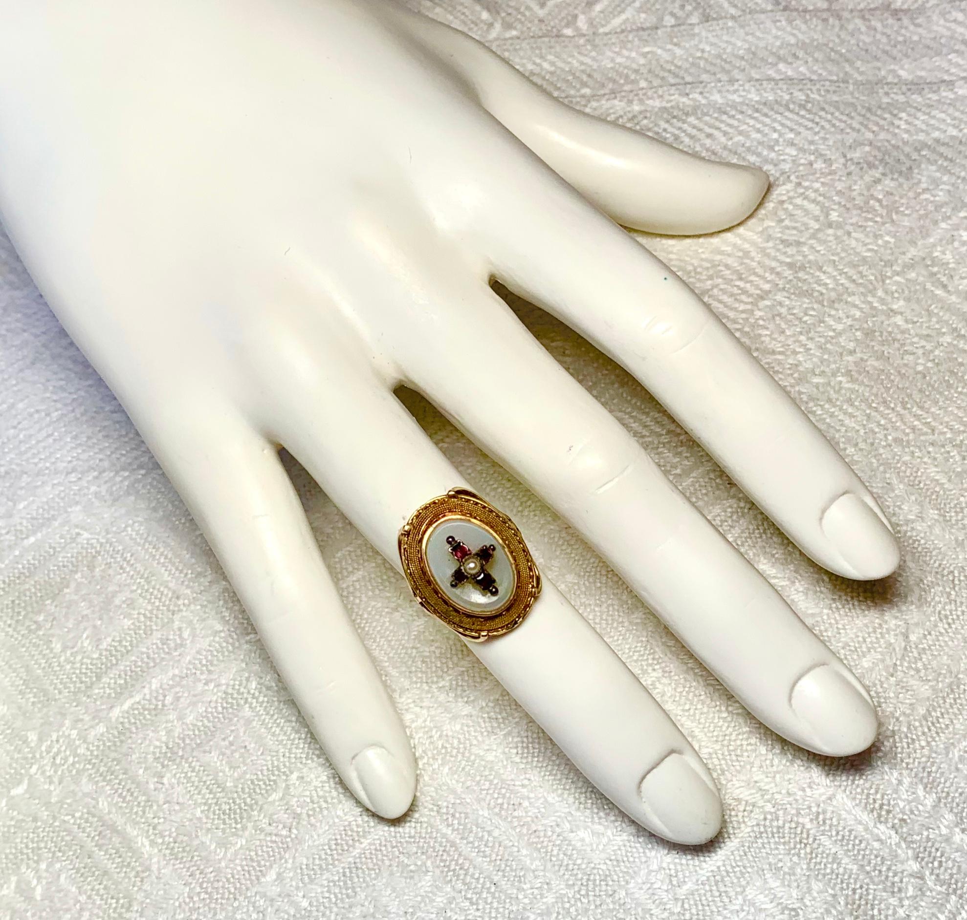 A gorgeous Antique Ring in the Etruscan Revival style with a Ruby Cross motif in the center set on a Chalcedony hardstone oval gem.  The jewels are set in 14 Karat Rose Gold.  The ring dates to the Victorian period, circa 1850-1890.  It has superb