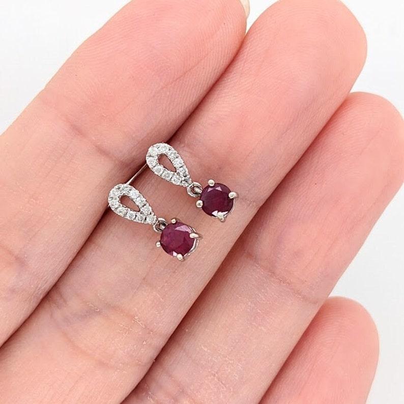Specifications:

Item Type: Earring Studs
Gold Purity: 14k
Gold weight: 1.88 grams
Diamonds: 20/0.12 cts

Stone Specs:
Type: Ruby
Weight: 0.64 cts
Shape: Round
Size: 4mm
Treatment: Heated
Hardness: 9
Origin: Madagascar

These studs are made with