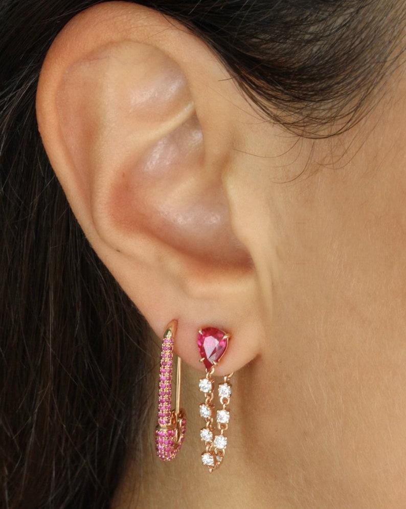 Cast in 14 karat gold, these earrings are hand set with 1.40 carats ruby and .50 carats of sparkling diamonds. Available in Rose, Yellow and White gold. Comes in pair, can also be bought as single earring. See other gemstone options, emerald and