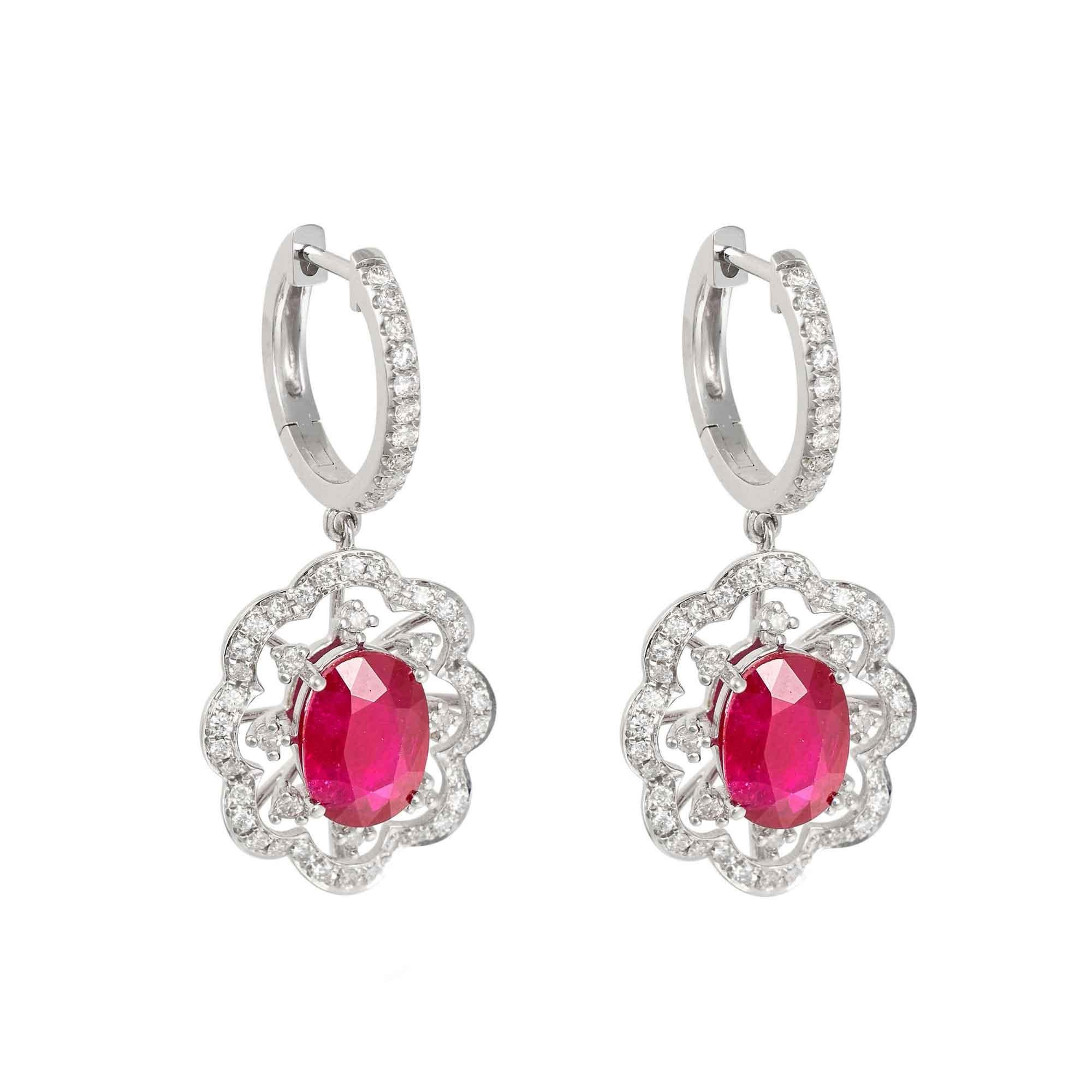 A pair of contemporary halo ruby drop earrings ring. Each featuring a central oval cut ruby, beautifully framed with a floral halo set with diamonds in 18ct white gold.

- Rubies 3.06ct
- Diamonds 0.557ct
- Dimensions (LxW): 30mm x 14mm
- Weight per