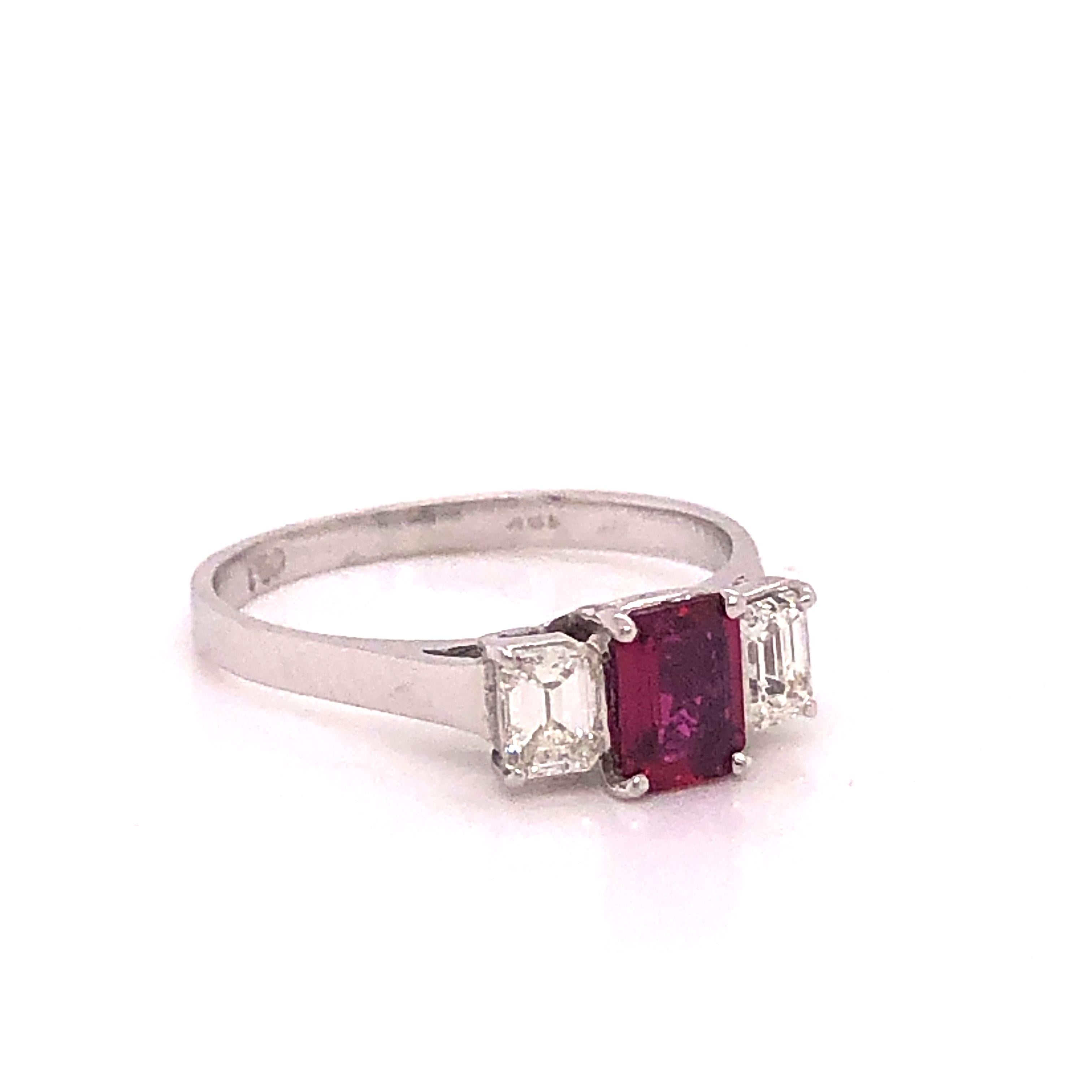 Amazing design on this simple yet majestic beauty. This ring is hand crafted out of 18k white gold.  This three stone design is highlighted with a center Ruby gemstone. The gemstone shows a lushious red color and is a emerald cut gemstone. The Ruby