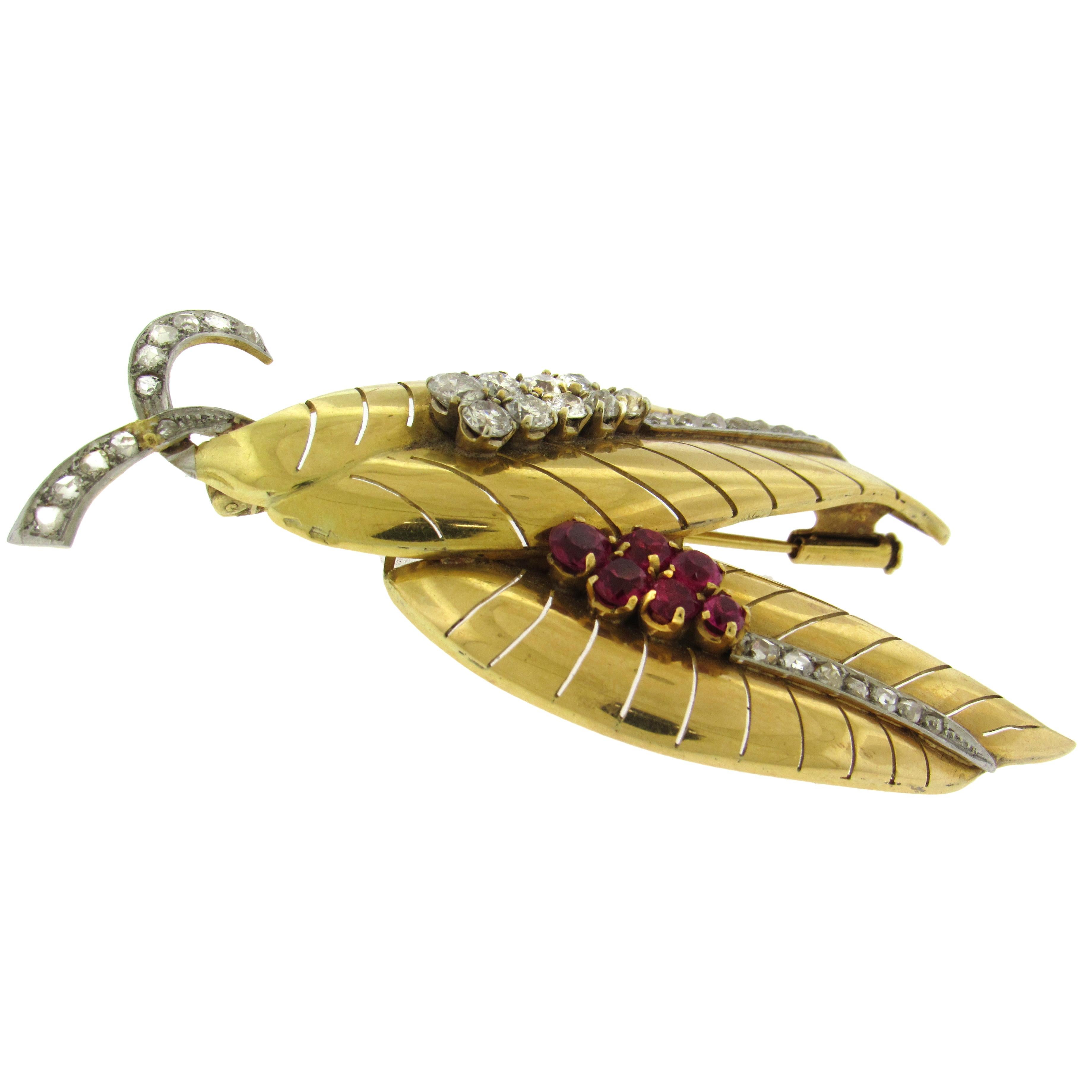 El alfiler de hoja estilizada de oro amarillo de 18 quilates presenta dos hojas dentadas de estilo tropical, engastadas con rubíes y diamantes de talla mixta europea antigua, moderna y rosa engastados en los tallos y las venas de las hojas. Sello