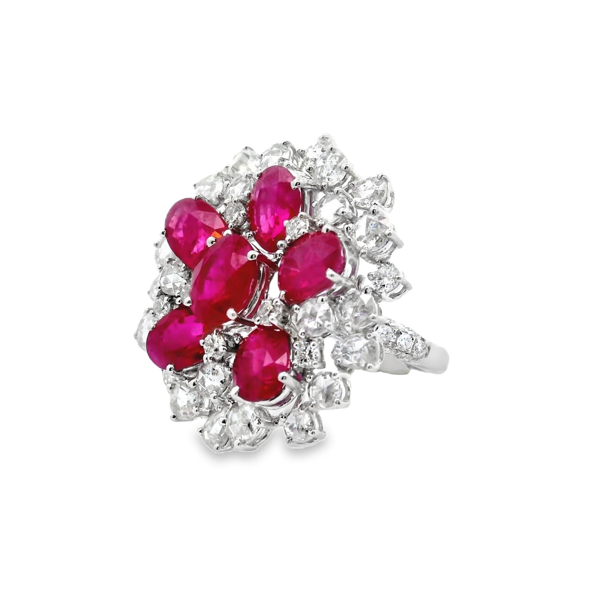 A stylish and brilliant cluster ring set with rubies and diamonds! There are a total of 6 oval-shape rubies weighing 7.01 carats that have strong and vibrant red color. They are surrounded and complemented by 3.40 carats of rose and round
