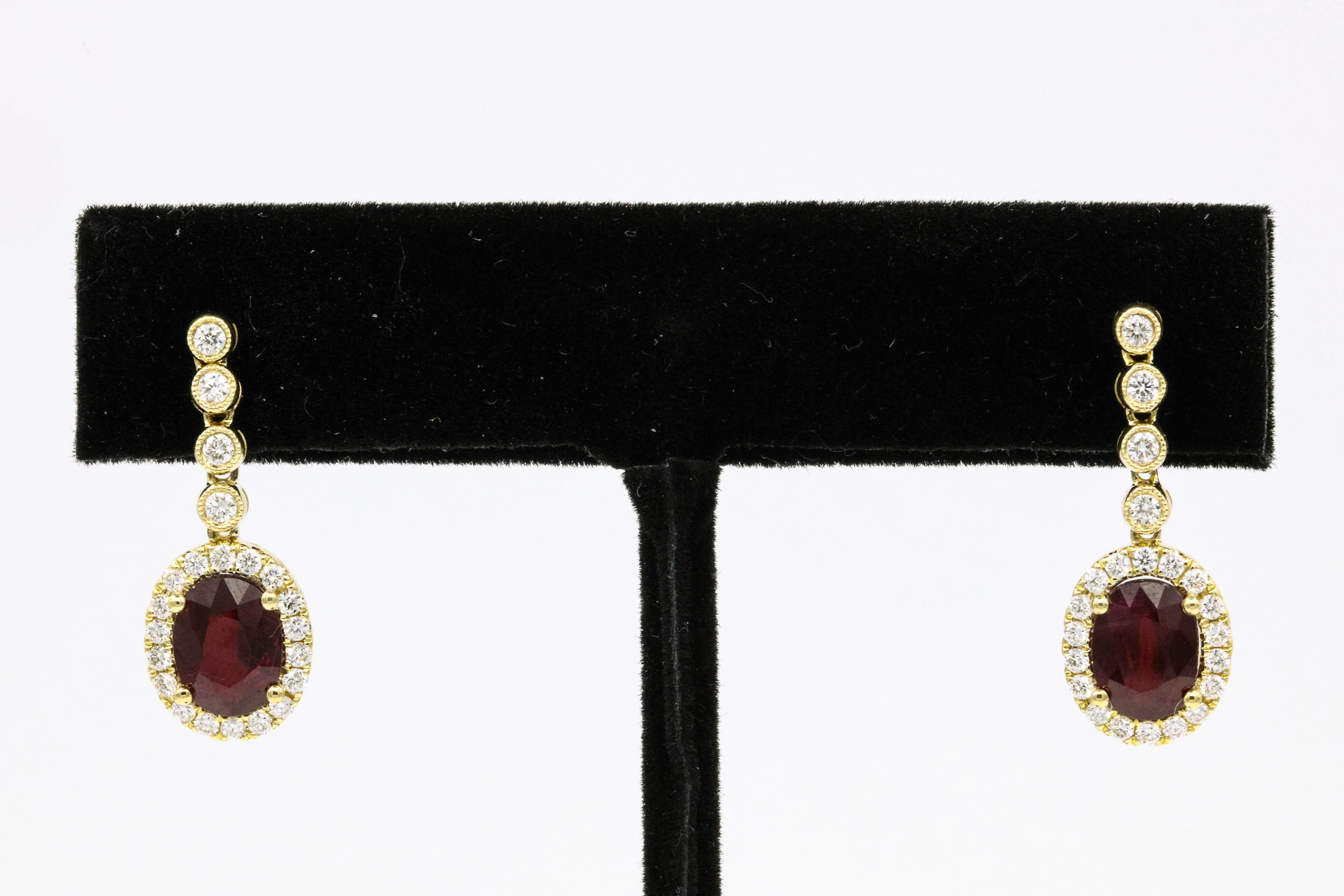 18K Yellow gold drop earrings featuring two oval shape red rubies 2.90 carats, surrounded by round brilliants weighing 0.56 carats.
Color G-H
Clarity SI