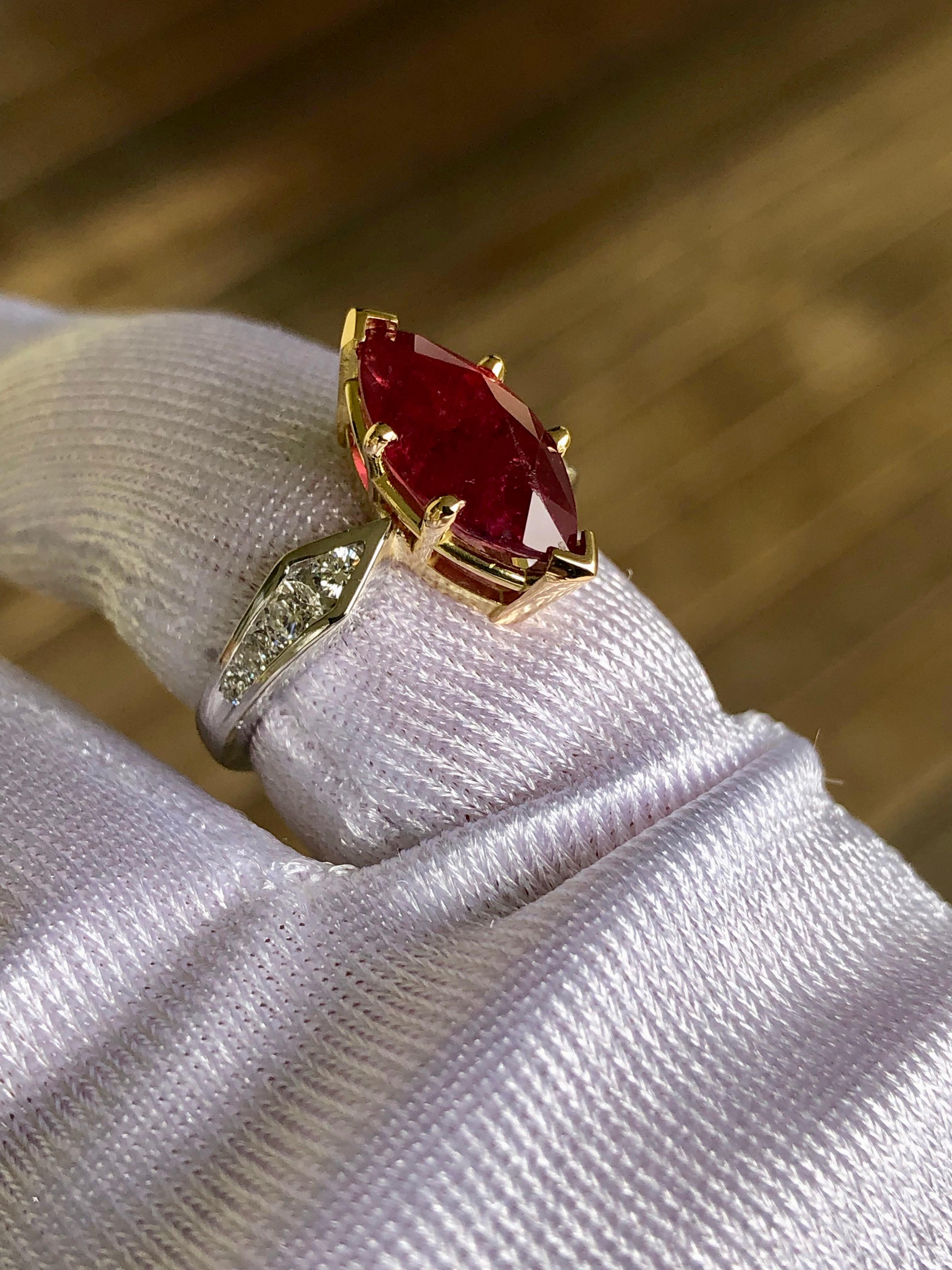 This stunning estate engagement ring stars a natural Mozambique deep, rich red ruby Marquise cut weighing approx. 3.50 carats flanked by brilliant-cut diamonds weighing over 0.40 carat (F color, VS1 clarity). This elegant ring is crafted in a