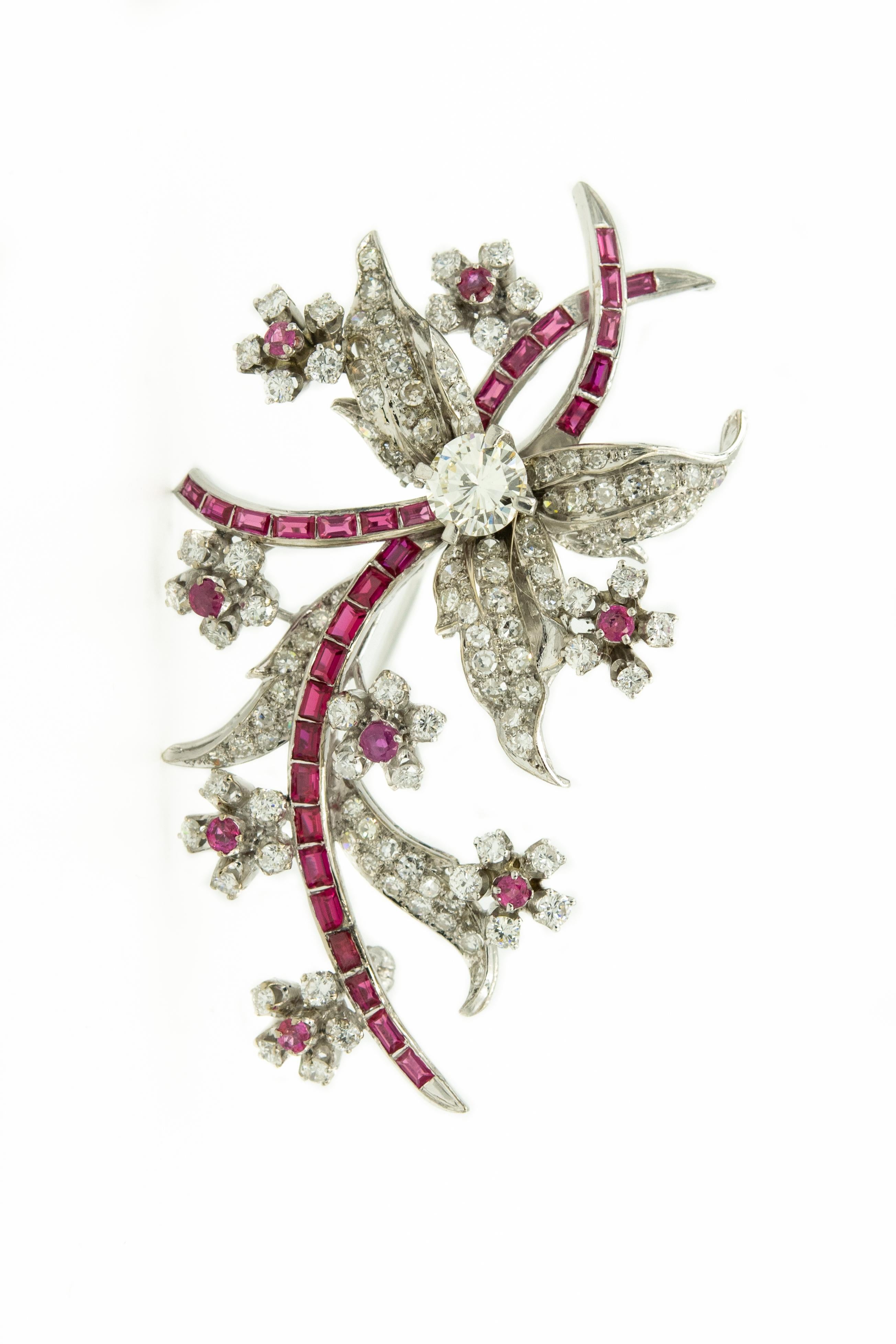 20th Century flower & leaf spray 18k white gold brooch with a channel set ruby stems and eight smaller diamond flowers with faceted ruby centers.  The larger flower has a diamond weighting approximately a 1.15 carats.  The are additional diamonds in