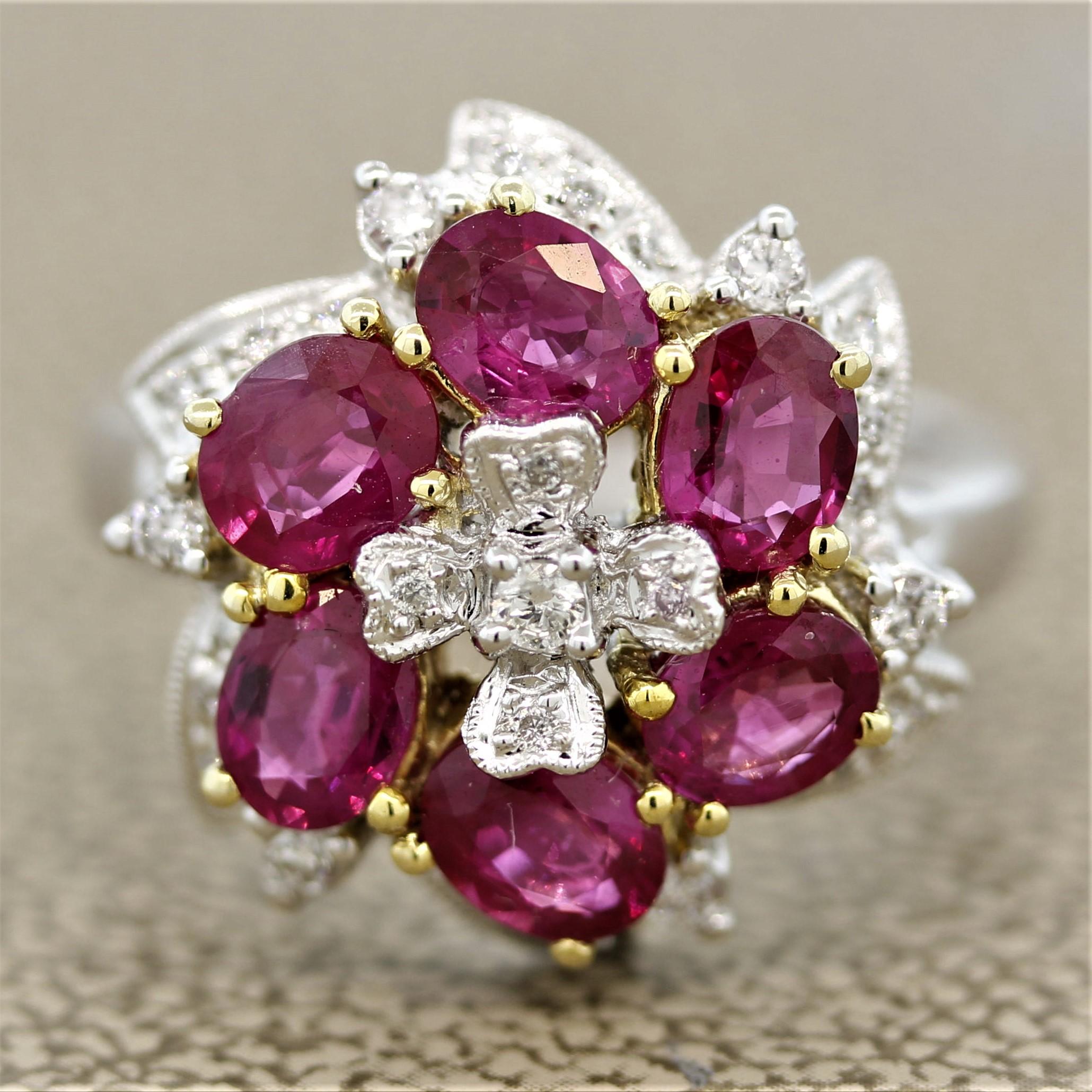 An elegant ring designed as a flower. It features 2.16 carats of oval shaped rubies that make up the petals. They have a bright pinkish-red color and are accented by 0.27 carats of round brilliant cut diamonds. Set in 18k white and yellow