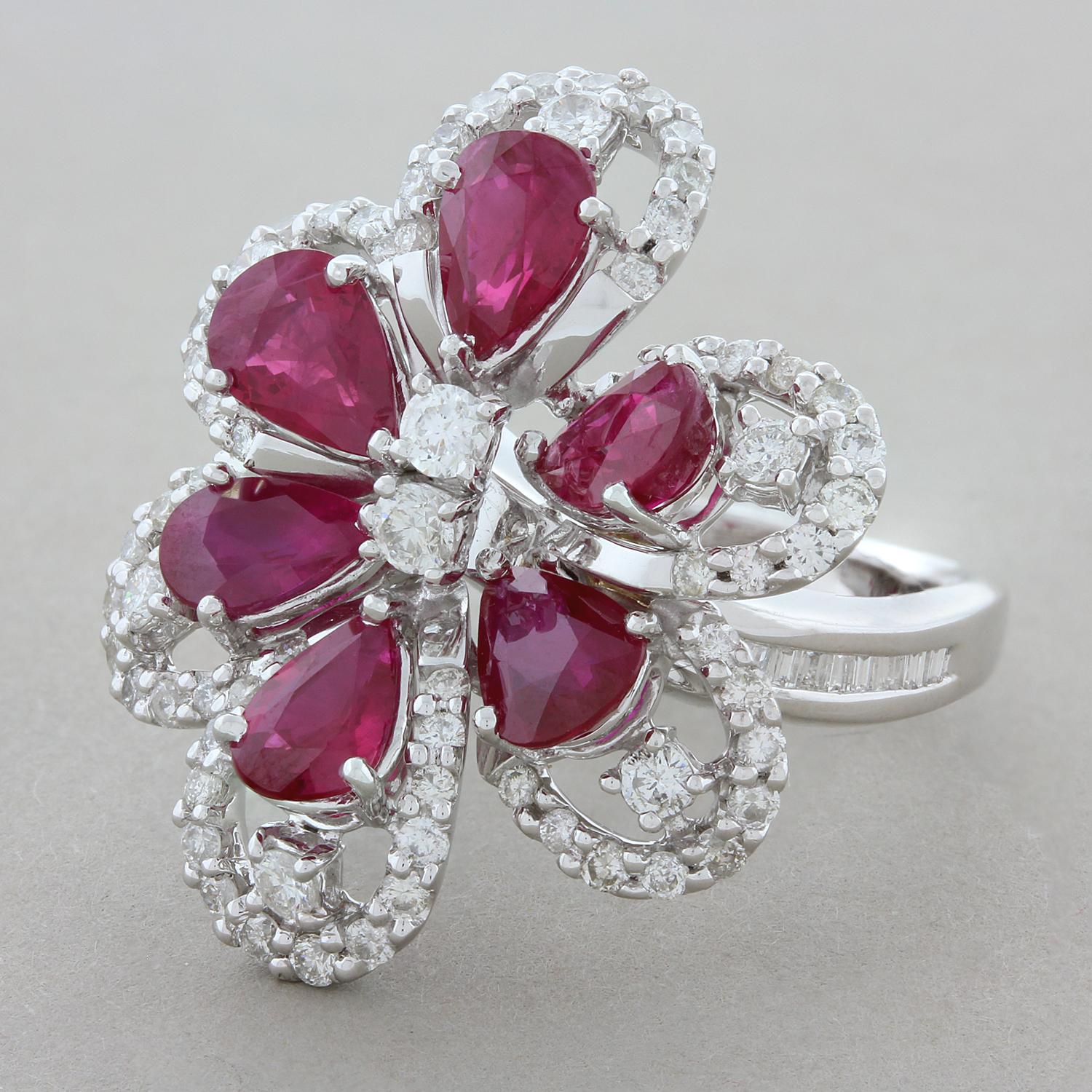 This free form flower ring features six vivid red rubies weighing a total of 4.88 carats. The pear shape rubies are accented by 1.76 carats of round brilliant cut diamonds with baguette cut diamonds channel set on the shoulders of this 18K white