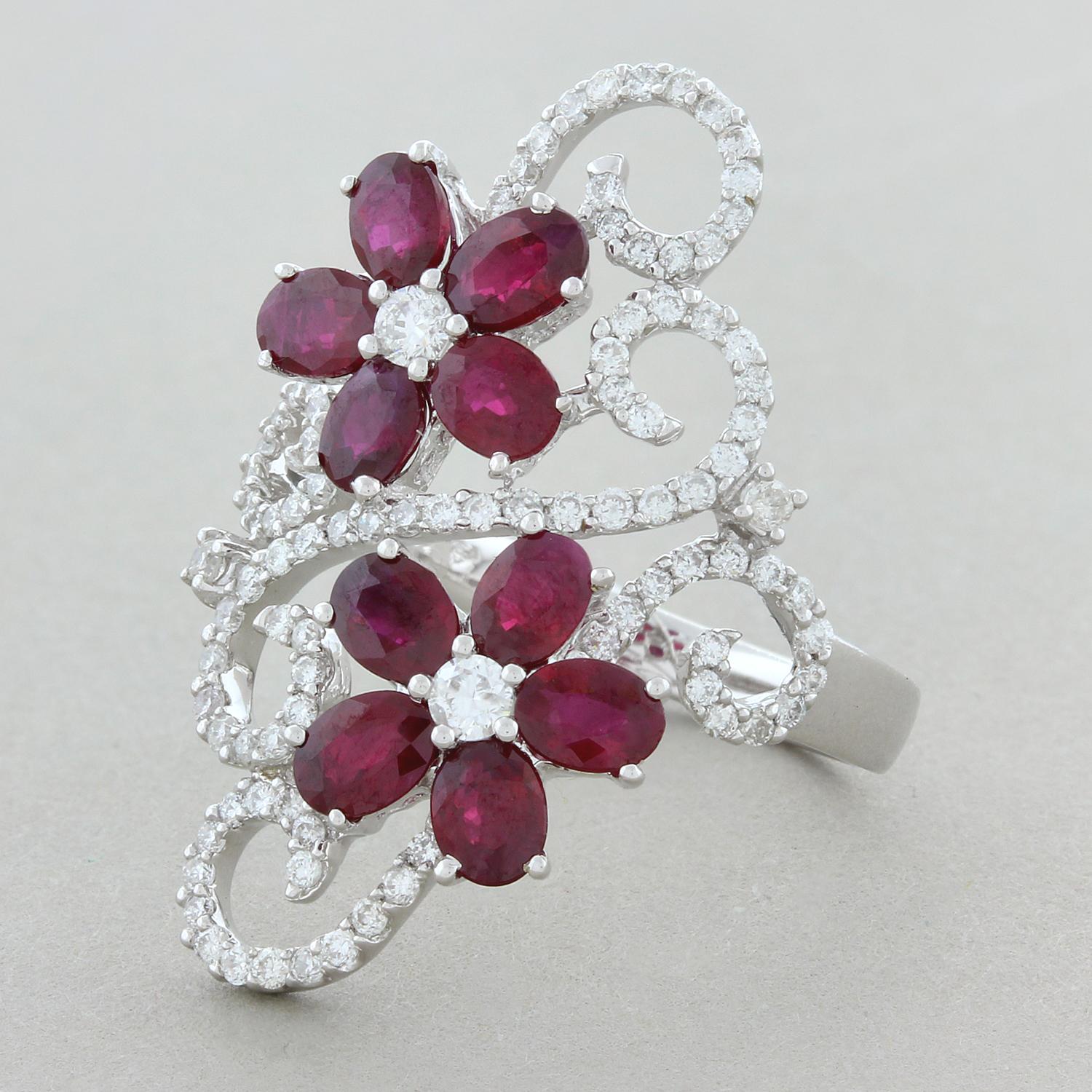 This everyday navette style cocktail ring features two side-by-side flower clusters. The two flowers are comprised of 2.28 carats of fine vivid red oval cut rubies and 0.70 carats of sparkling round brilliant cut diamonds which accent the rubies