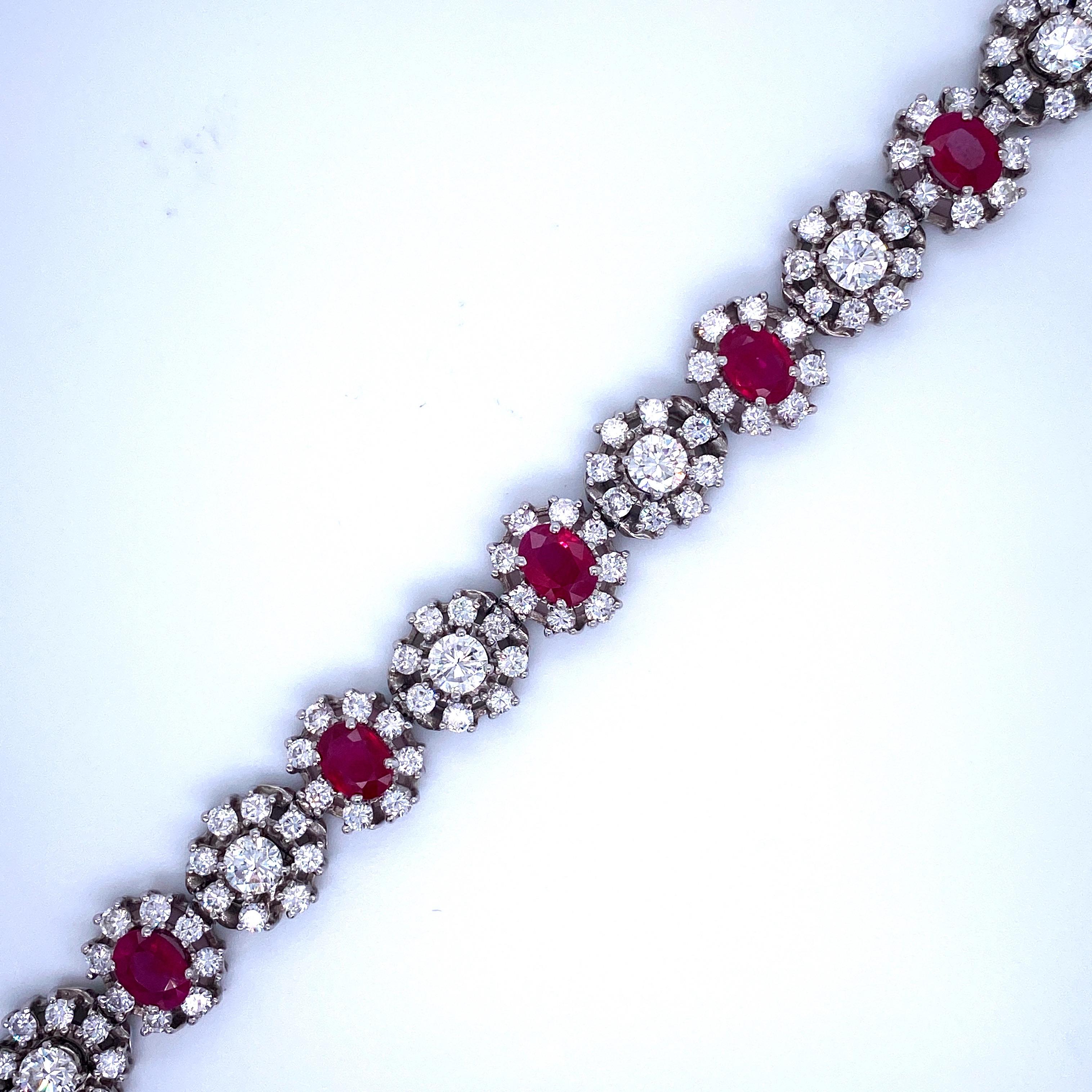 Platinum cluster motif bracelet featuring alternating oval cut rubies and round brilliant diamonds surrounded by diamond halos. 
Ruby- 5.2 * 7.14 mm
Ruby Carat Weight: Approximately 8 Carats
Diamonds Carat Weight: Approximately 10 Carats 
Color