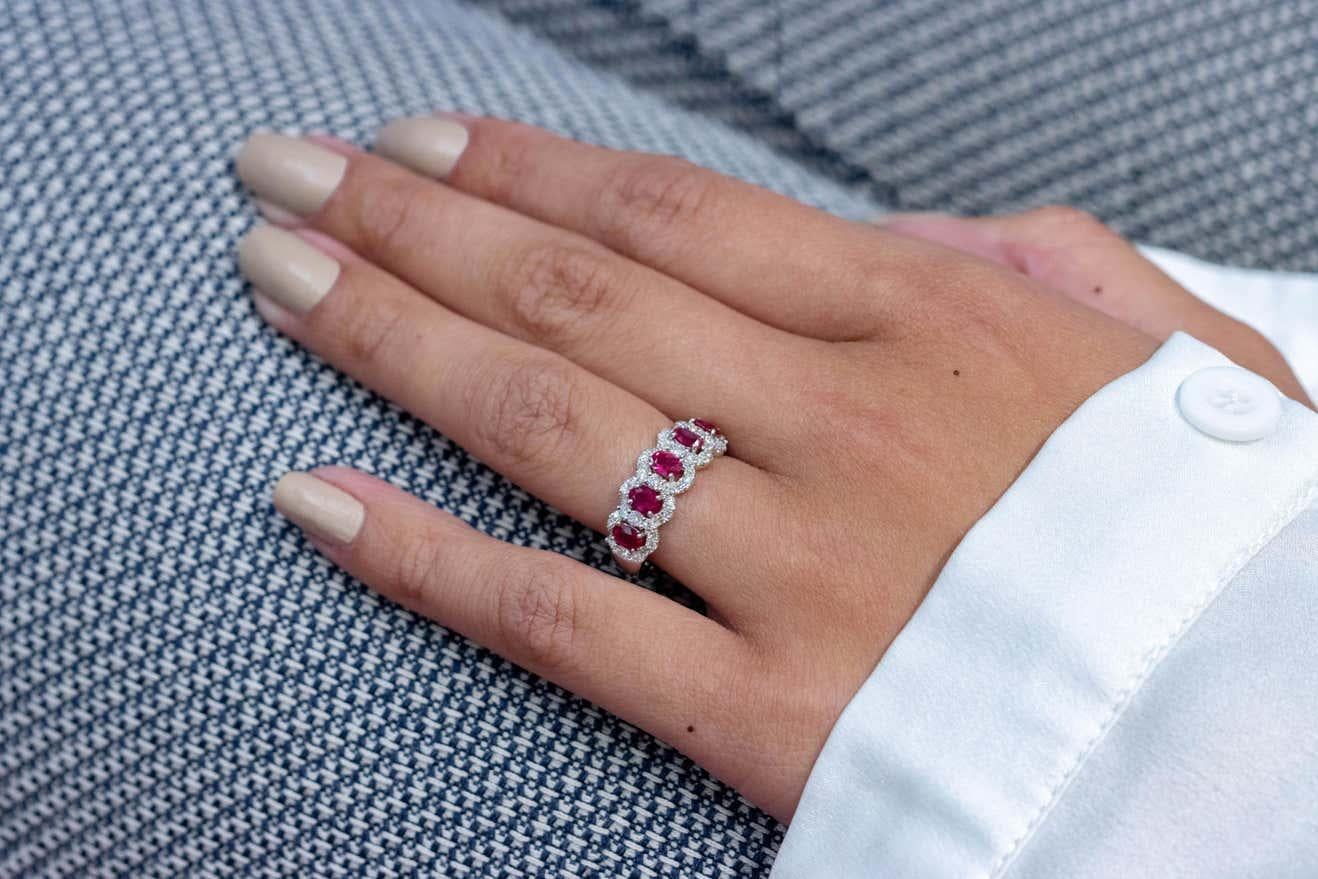 Beautiful ring set with 5 oval cut rubies weighing 1.04 carats total. Each ruby is surrounded by a single row of  round cut melee diamonds weighing 0.59 carats total. Set in 18k white gold. Sizable upon request.

Style available in different price
