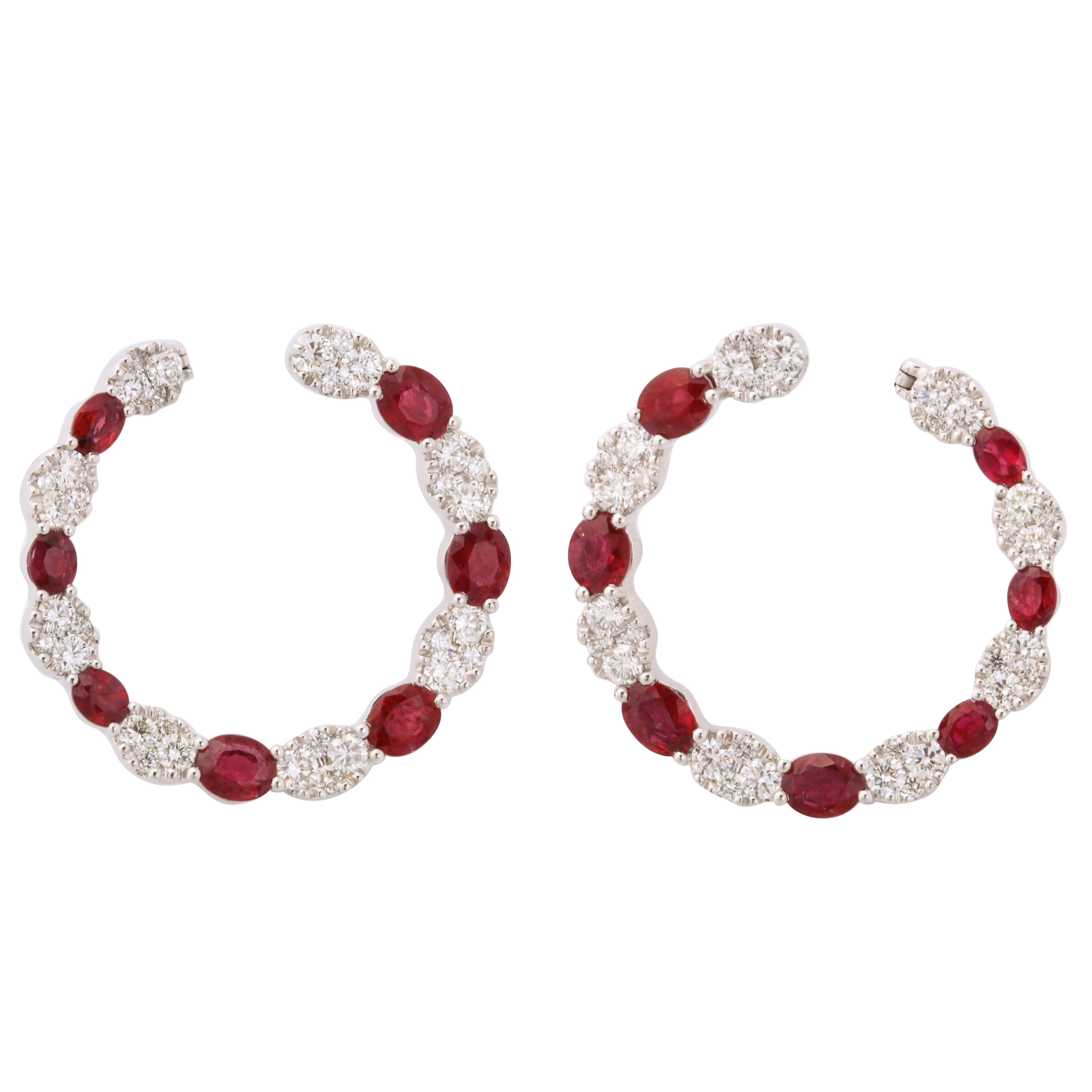 Bright red oval rubies (4.98cts) and round diamonds configured in an oval formation (2.54cts) alternate in this bold and dramatic hoop earring.  Easily wearable from day into evening these earrings will never fail to be noticed.  With a diameter of