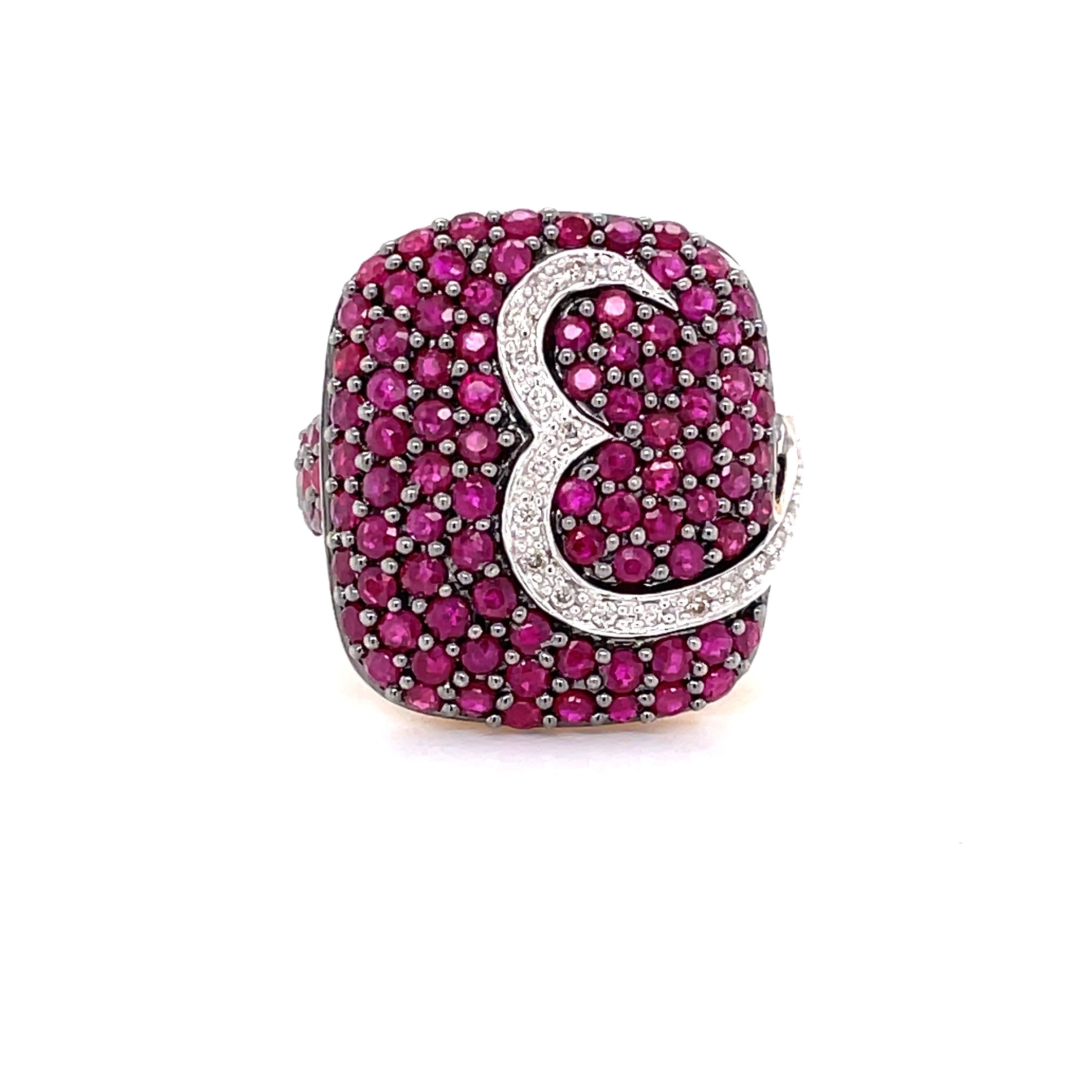 Three carats of cheerful and bright fuchsia round faceted full cut rubies accented with an artful brush stroke of diamond pave decorate the square shaped head of this fourteen karat 14K  yellow gold contemporary style ring. The slightly domed head