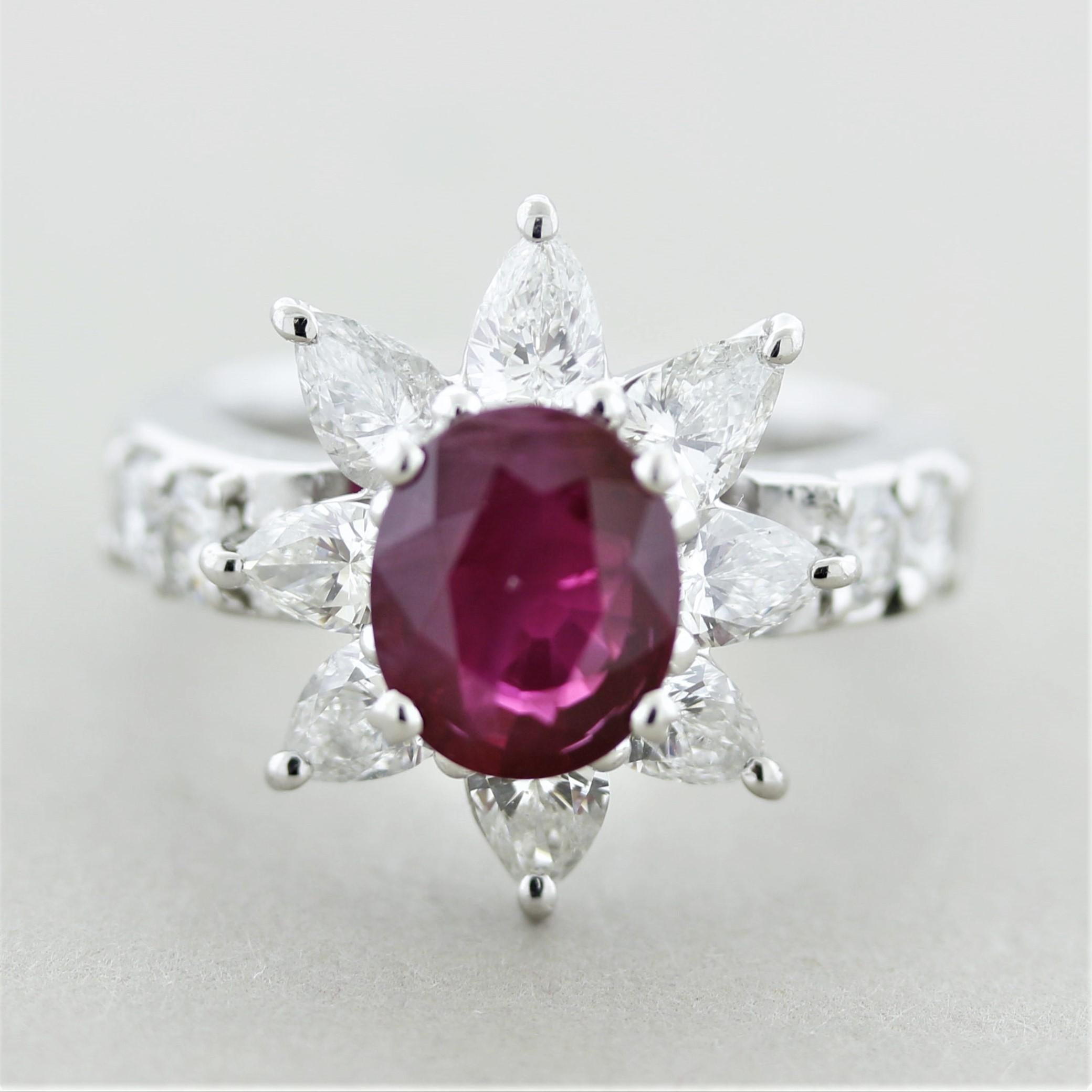 A superb oval shaped ruby weighing 2.05 carats takes center stage of this flower themed ring. The ruby is certified by the GIA as natural and has a lovely rich red color. It is accented by large pear-shaped diamonds set on its outsides creating a