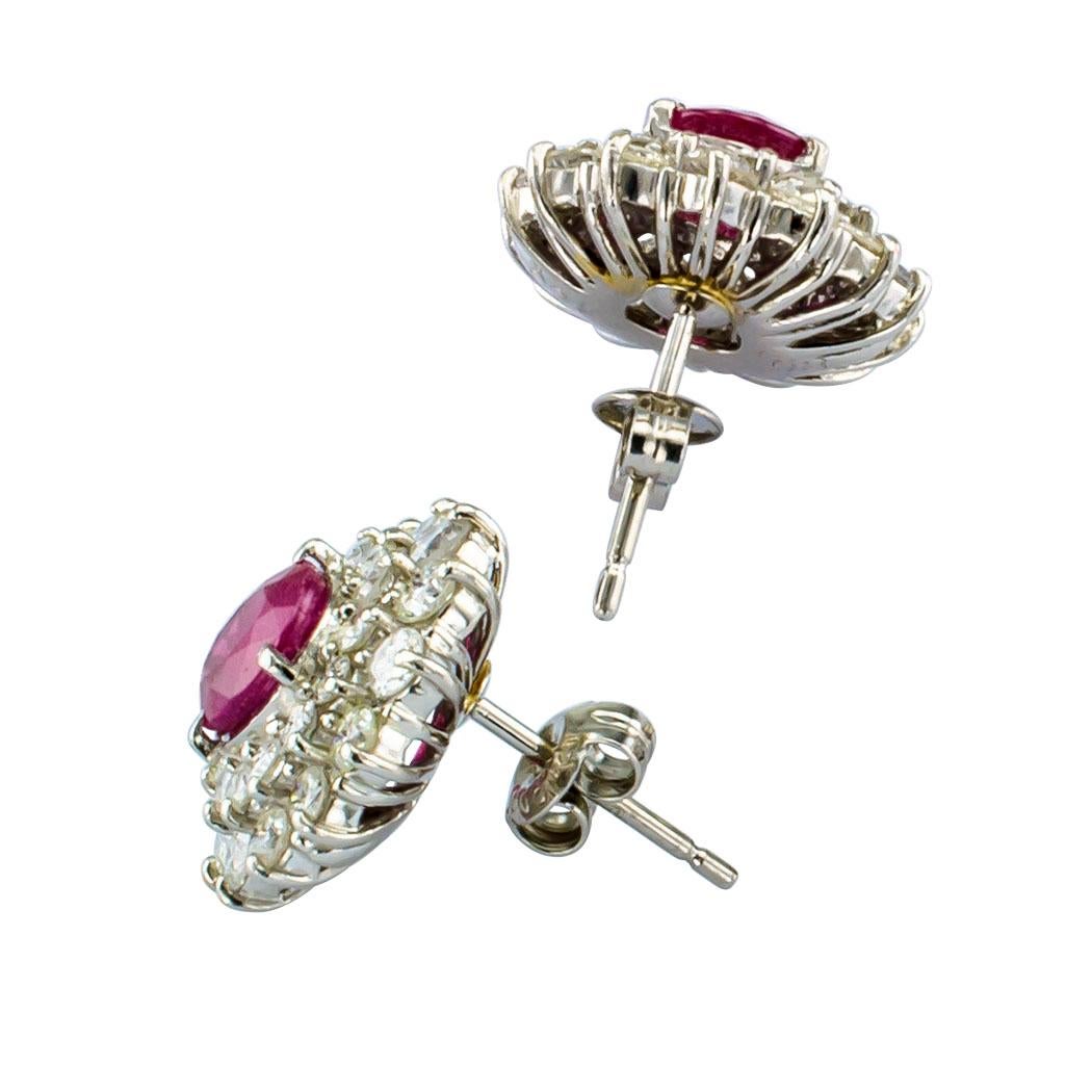 Ruby and diamond stud earrings mounted in platinum. Featuring a pair of faceted oval rubies together weighing approximately 2.14 carat, within a conforming, double-stepped border of round brilliant-cut diamonds totaling approximately 1.82 carat,