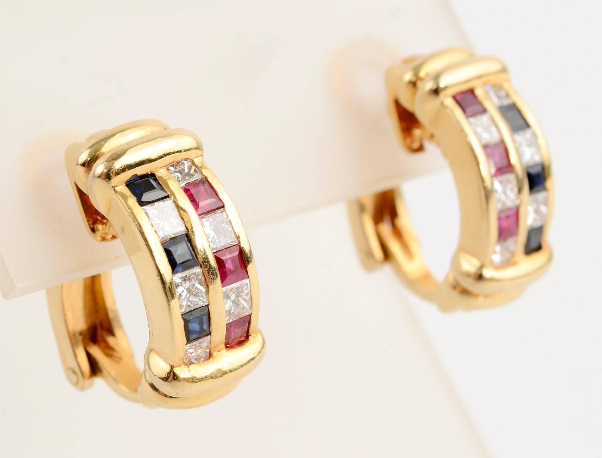 Colorful half hoop earrings in which a row of rubies alternating with diamonds abuts a row of sapphires with diamonds. Placing the stones in a stepped pattern adds visual interest. Horizontal bars of gold frame the stones top and bottom. Backs are