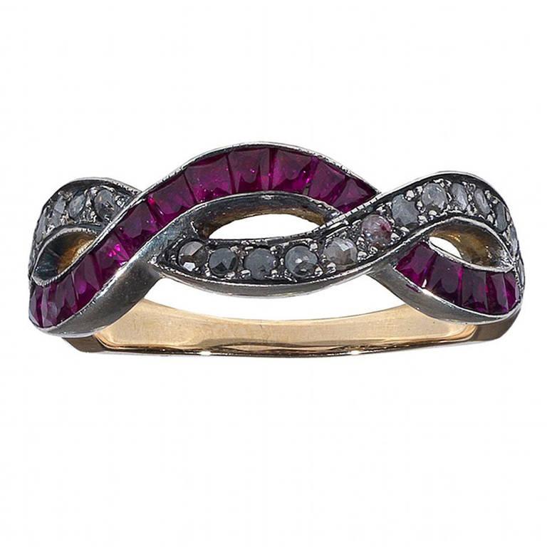 PLEASE NOTE: OUR PRICE IS FULLY INCLUSIVE OF SHIPPING, IMPORTATION TAXES & DUTIES.
A crossover shape ring with calibre cut ruby and rose cut diamonds.
Mounted in silver and gold.

Size: 6 1/2
Weight: 3 gr