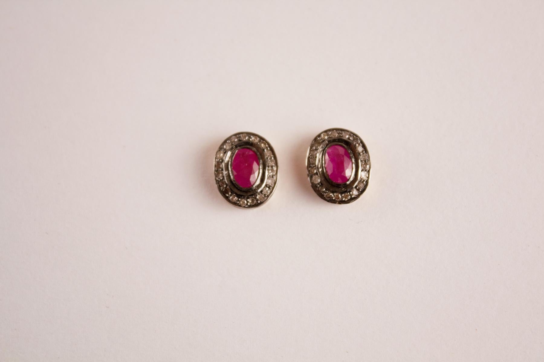 Faceted rubies are encircled by flat cut, pave set diamonds in these oval shaped studs. The handwork is intentionally unrefined, which makes the earrings a bit more casual and wearable. The studs are sterling silver washed in 14 karat gold. Posts