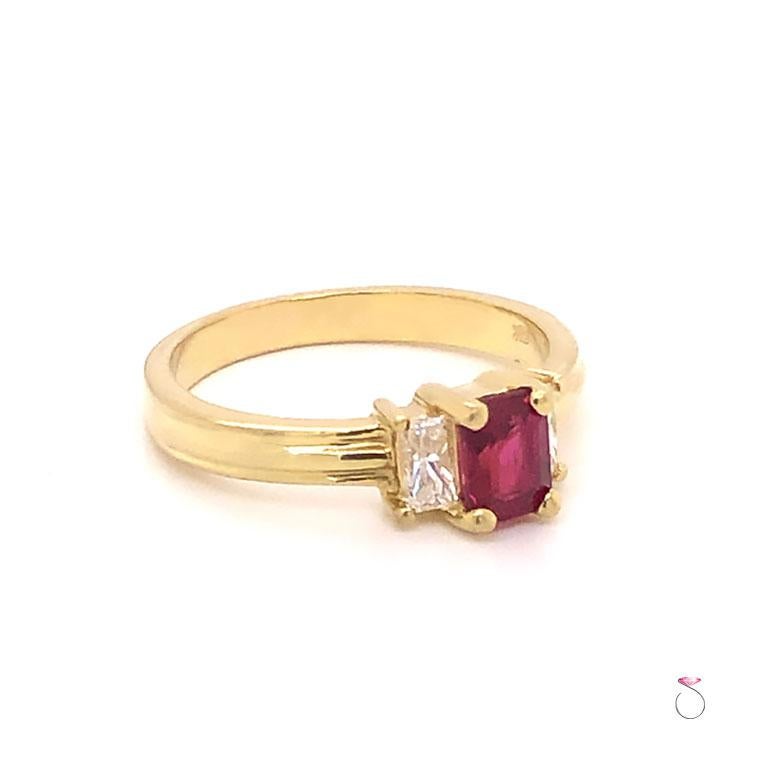 Pretty Ruby & diamond three stone ring in 18K yellow gold. This ring features a stunning Emerald cut Red Ruby in the center, flanked by two radiant cut diamonds, one on each side. The ruby and the diamonds are each set in four prongs. This gorgeous
