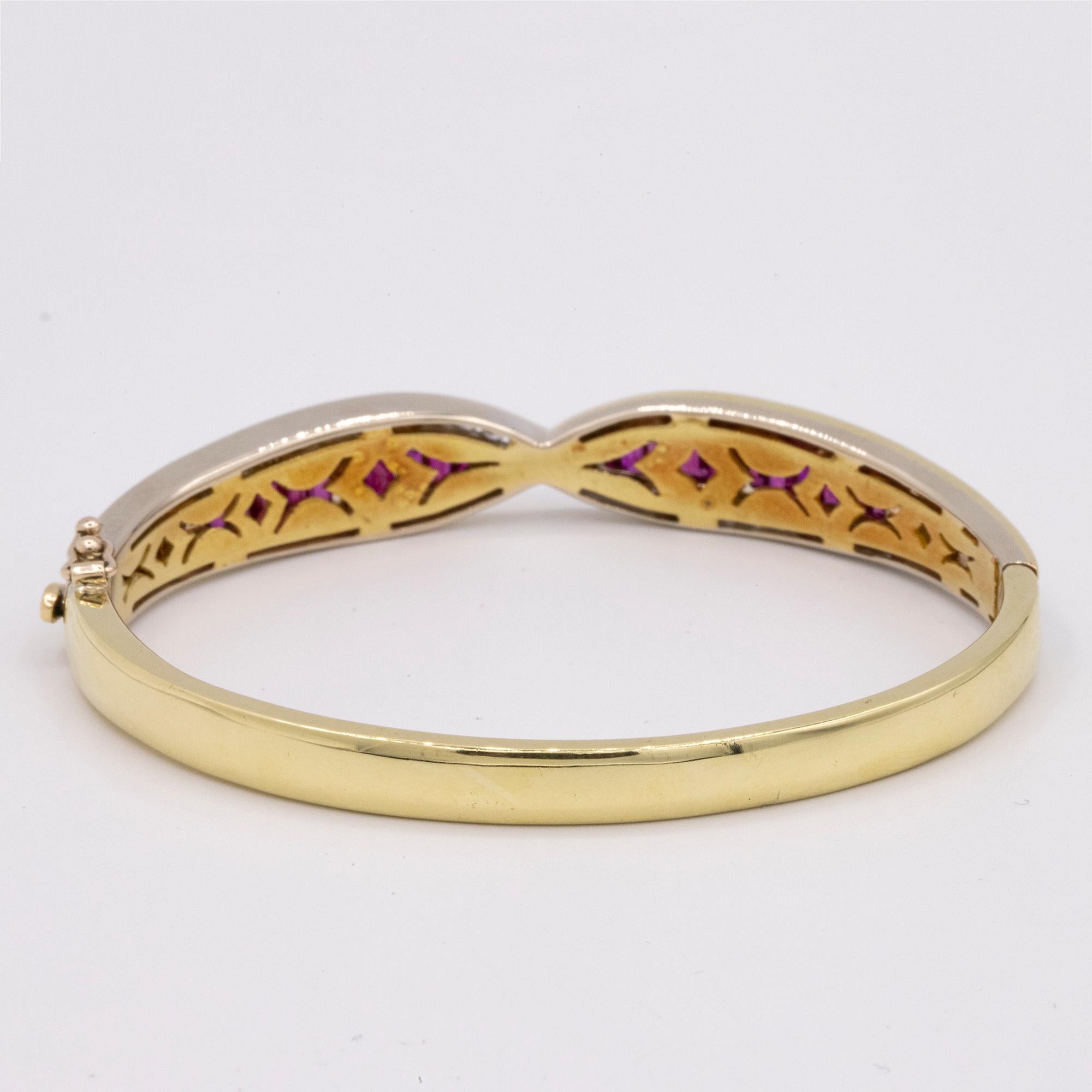 18kt Yellow & White Gold Crossover Ruby & Diamond hinged bangle bracelet. The bracelet has 20 Baguette cut Rubies (10 Channel set on each side) and 29 Round Diamonds channel set weighing approximately .30 carats.