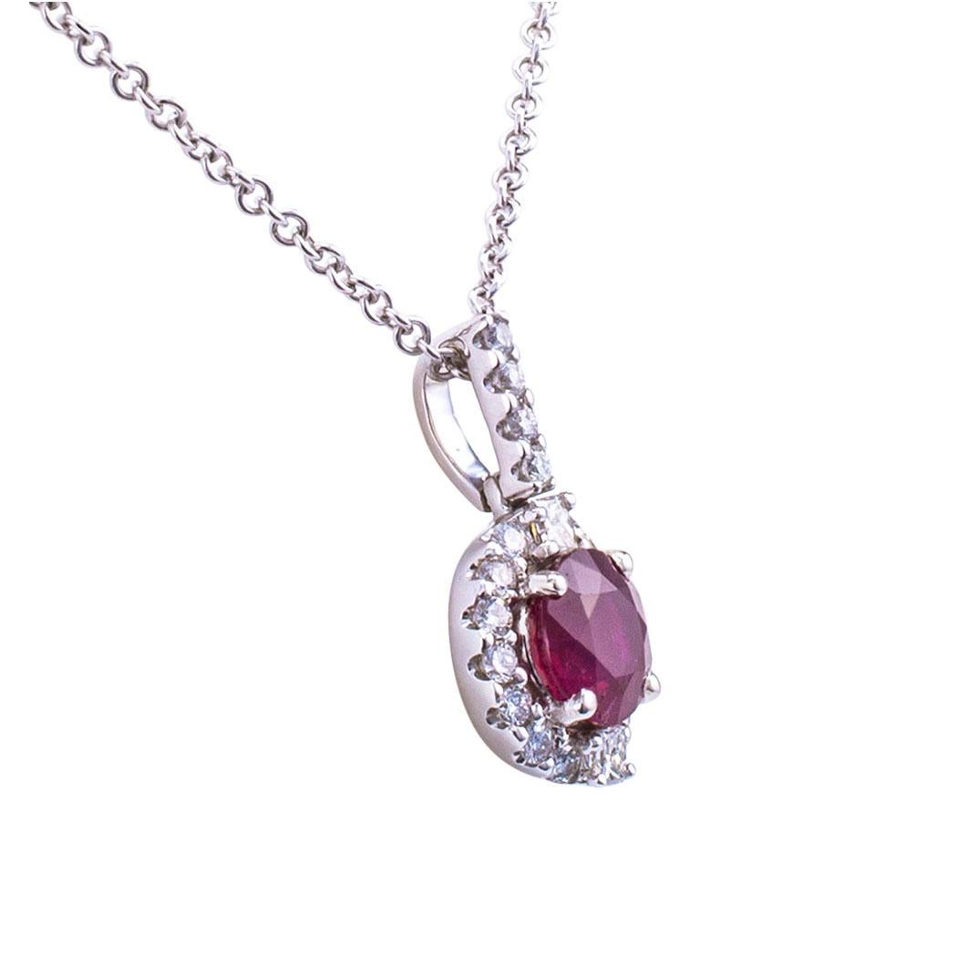 Ruby diamond and white gold pendant. Showcasing a faceted, round ruby weighing approximately 0.79 carat, within a conforming border to the articulated bail, both set with small, round brilliant-cut diamonds totaling approximately 0.24 carat,