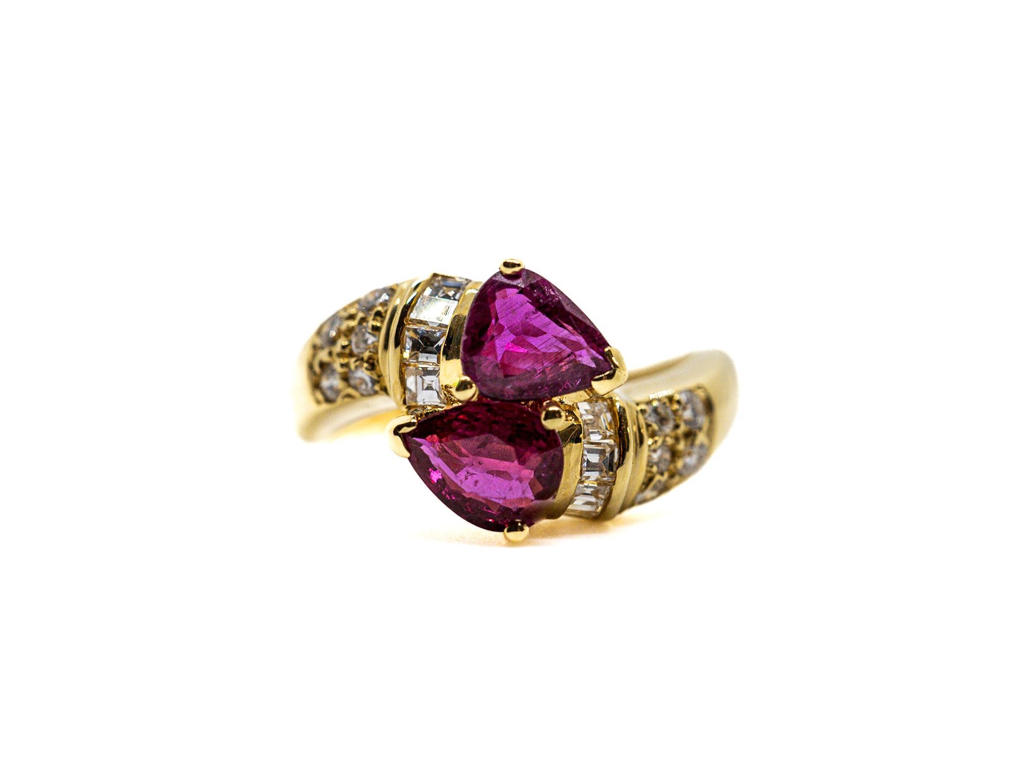 Dieser Ring aus 18 Karat Gold zeigt zwei birnenförmige Rubine, die von einem Cluster aus Baguette-Diamanten und kleineren Diamanten mit einem Gesamtgewicht von etwa 0,5 ct umgeben sind. 

Die Rubine verleihen dem Ring ein leuchtendes Rot, während