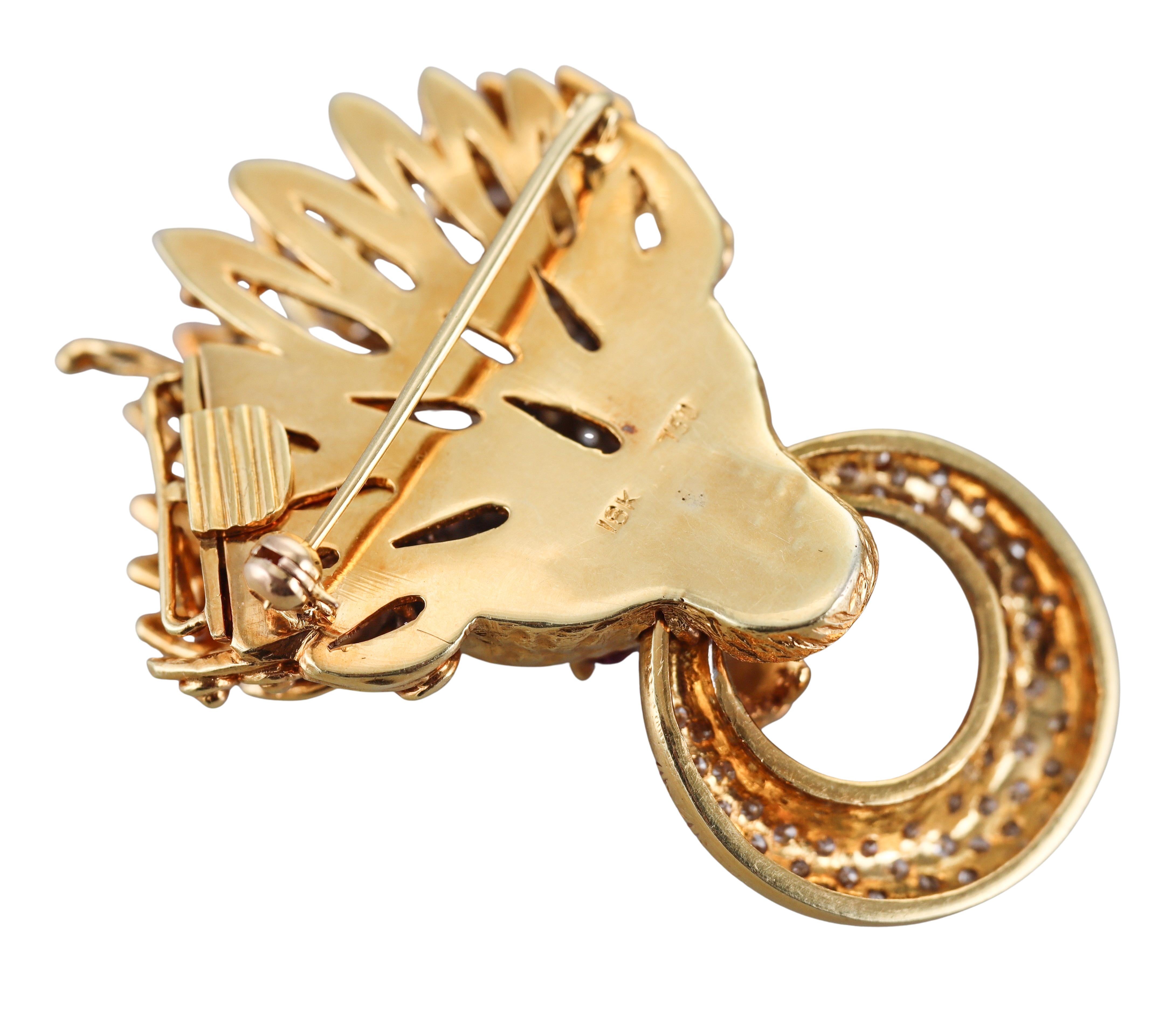 An 18k yellow gold brooch/pendant, depicting a lion's head, adorned with ruby cabochon eyes and approx. 1.50ctw in H/Si1 diamonds. 
The piece measures 2