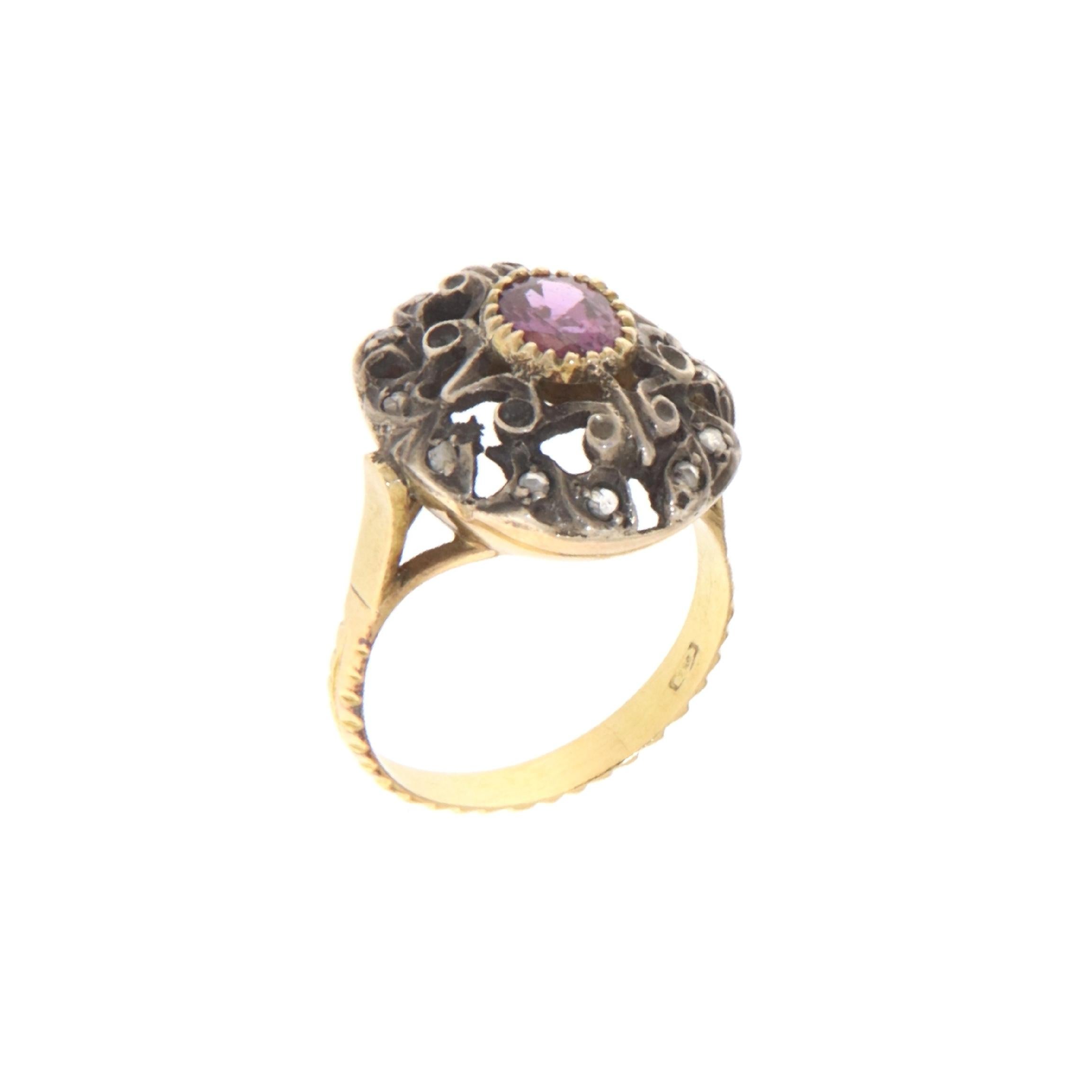 This exquisite ring harmoniously blends 18-karat yellow gold with 800 silver to create a piece that's rich in texture and history. At the center, a radiant ruby takes pride of place, its deep pink hue a symbol of passion and love. The ruby is