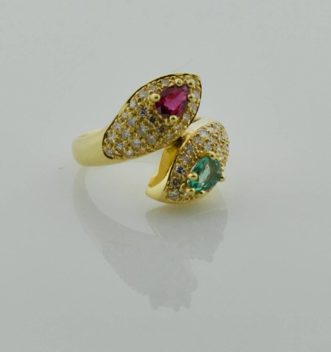Ruby, Emerald and Diamond Crossover Ring in18k Yellow Gold
One Pear Shape Ruby weighing .55 carats approximately
One Pear Shape Emerald weighing .40 carats approximately
Fifty Five Round Brilliant Cut Diamonds weighing 1.05 carats approximately GH