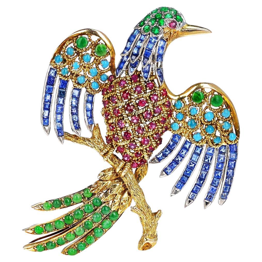 A Bird Brooch/Pin made with cut-stones of Ruby, Emerald, and Sapphires and with cabochons of Turquoise and Jade Bird Brooch/Pin. The brooch is made in 14k Yellow Gold. The length of the brooch is 3 inches and the width is 2 inches. The total weight