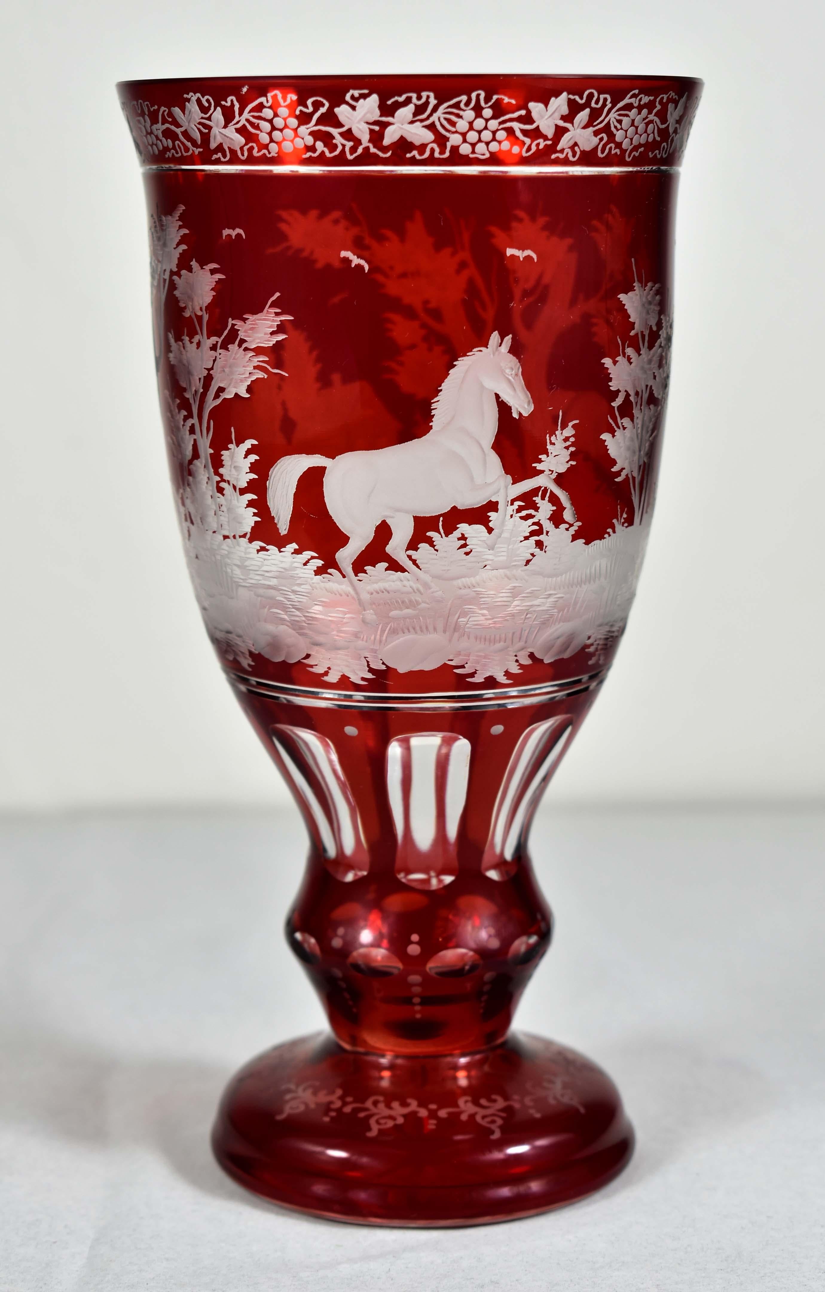 Clear glass goblet with ruby lazure. The goblet is cut, polished and engraved. Engraved motif of horses and architecture in the background, all complemented by an ornamental engraving and an engraving of vines. A very typical and popular 19th