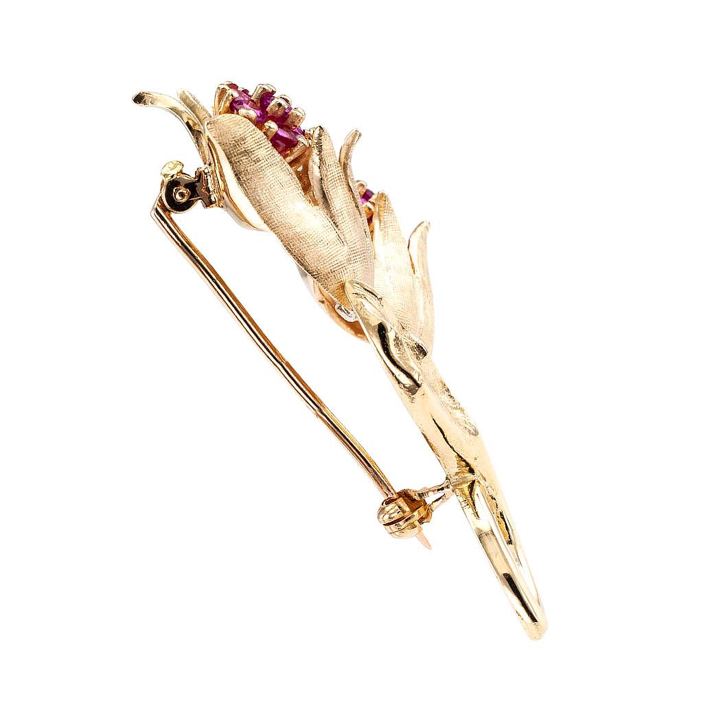 Estate ruby and gold twin tulip brooch circa 1960.

DETAILS:
GEMSTONES: fourteen round faceted rubies totaling approximately 1.50 carats.

METAL: 14-karat yellow gold decorated by organic textures.

MEASUREMENTS: approximately 2” (5.0 cm) long and 1