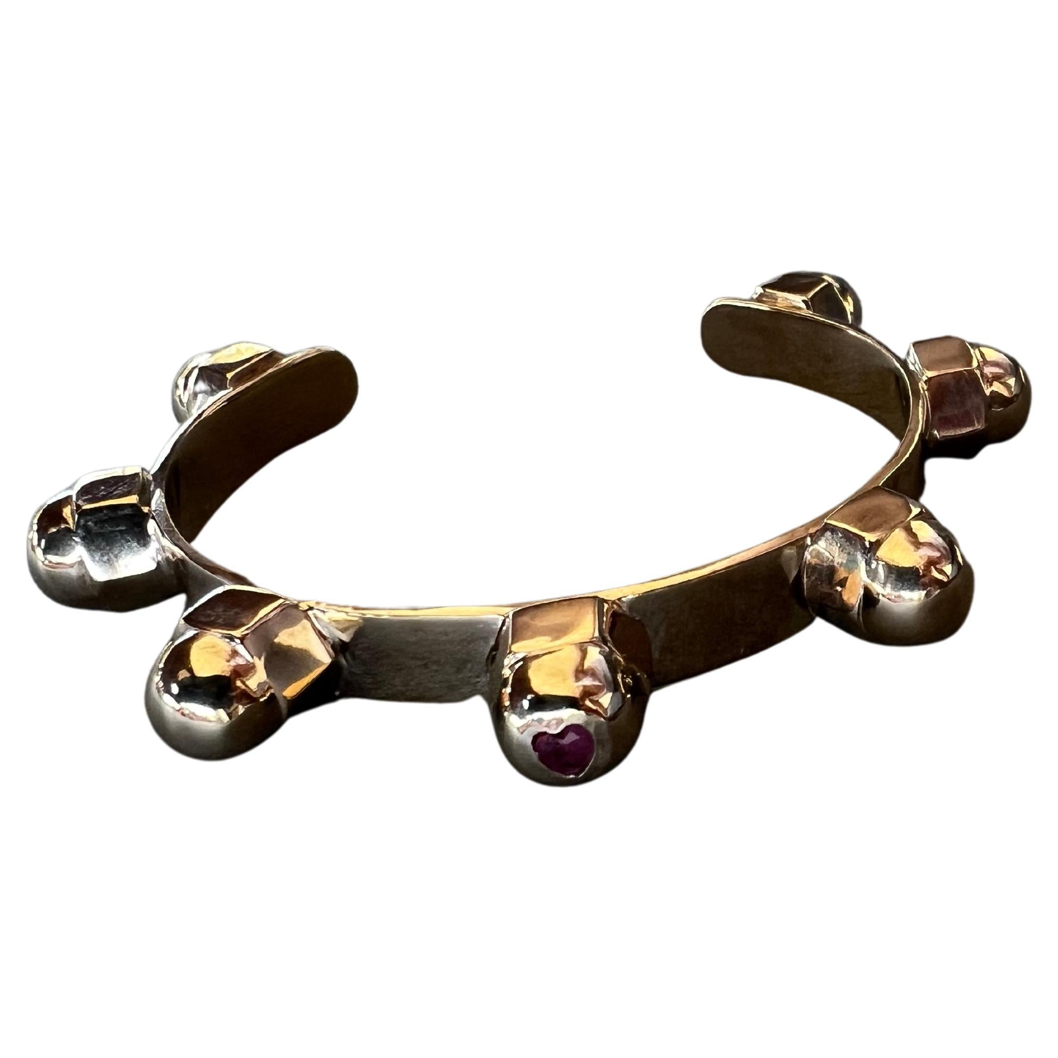 Ruby Heart Gem Cuff Bangle Bracelet 7 Studs J Dauphin

Material: Polished Bronze

Size Small/ Medium

Designer: J DAUPHIN

The Ruby gemstone is a timeless symbol of love, passion, and strength. Known for its deep red color and remarkable brilliance,