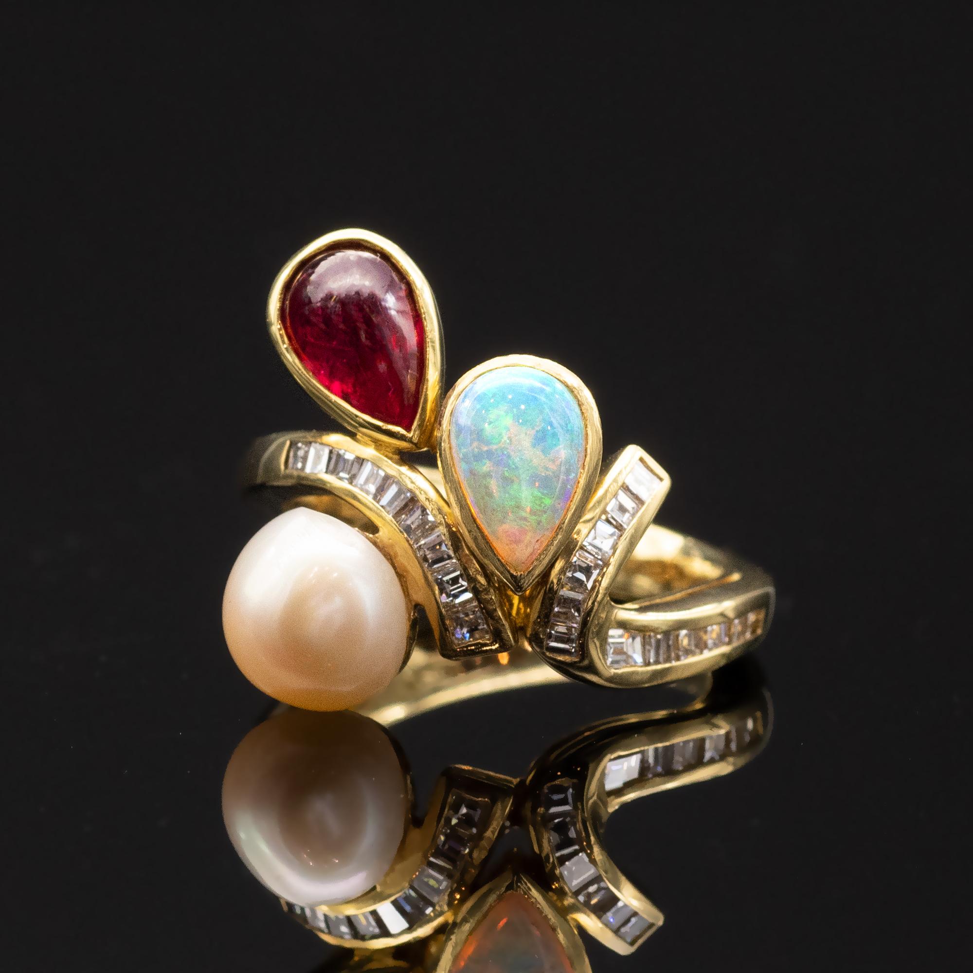 A truly elegant one of a kind Ring, A pear shape opal a cabochon ruby as well as a round pearl  are delicately placed on both sides of a shank. They seem to defy gravity. The shank itself has the graceful stem like movement  is set with 21 square