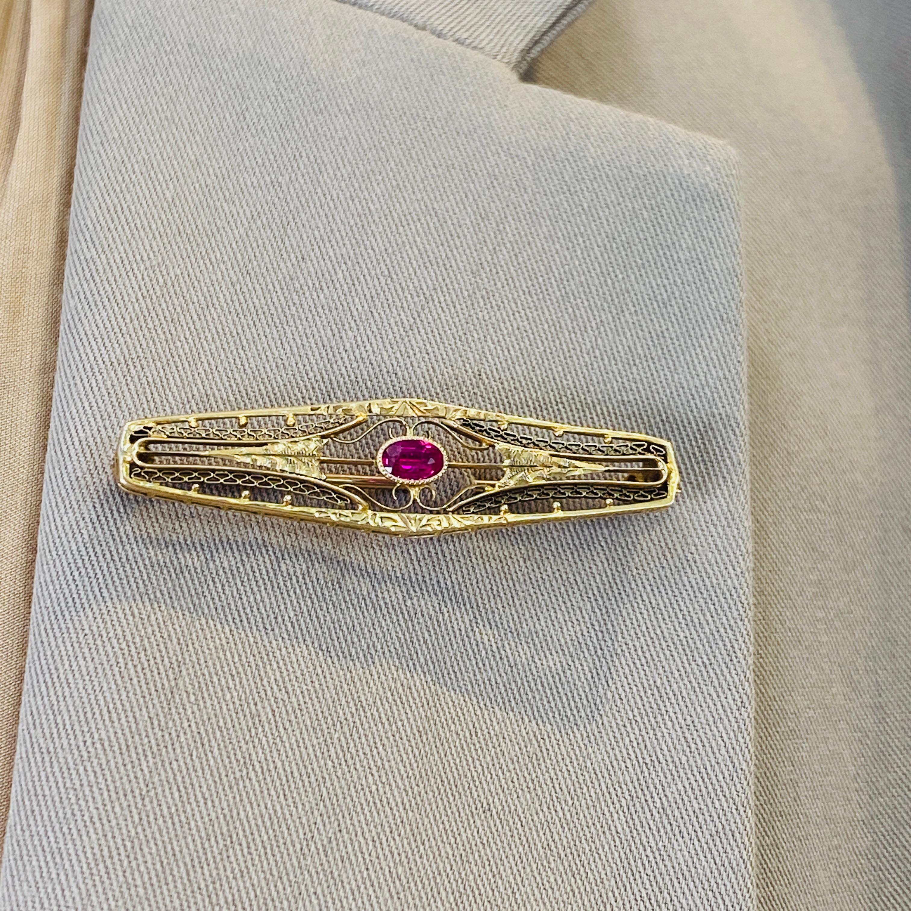 Perfect for the vintage jewelry lover, this gorgeous ruby brooch is beautifully made in 14 karat yellow gold! Fine wirework netting and diamond-cut details make this a beautifully intricate piece that reveals more details from every new angle you