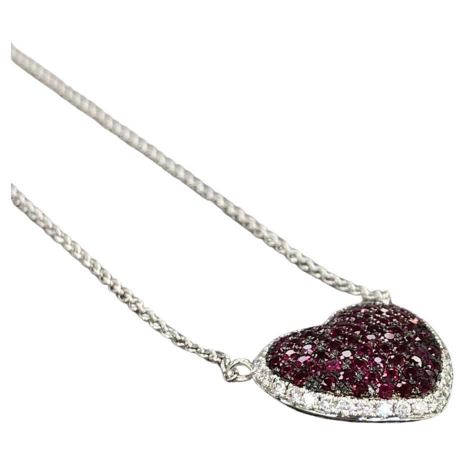 A stunning ruby pendant crafted from 18k white gold, featuring a 1.15ct ruby and diamond pave set heart design. It is securely attached to a 16'' chain. This exquisite piece is brand new, made of 18K white gold, weighs 4 grams, and measures 14.13.5