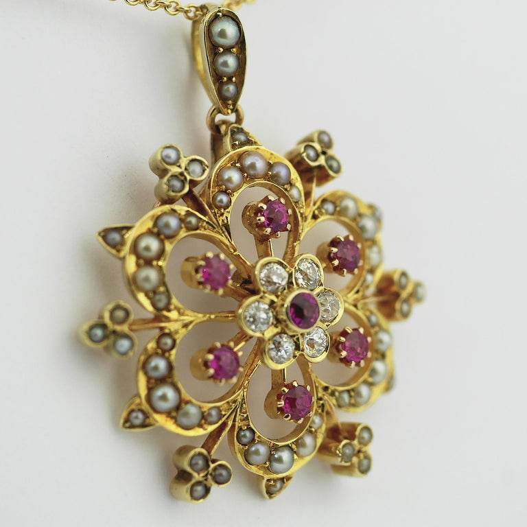 Victorian Pendant/Brooch in 15 carat yellow gold with rubies, pearls and diamonds in a starburst floral design, circa 1850

15 carat gold Ceylon rubies, half pearls and diamond set.

Rubies, Ceylon, natural untreated, 0.6ct total (approx)

Half