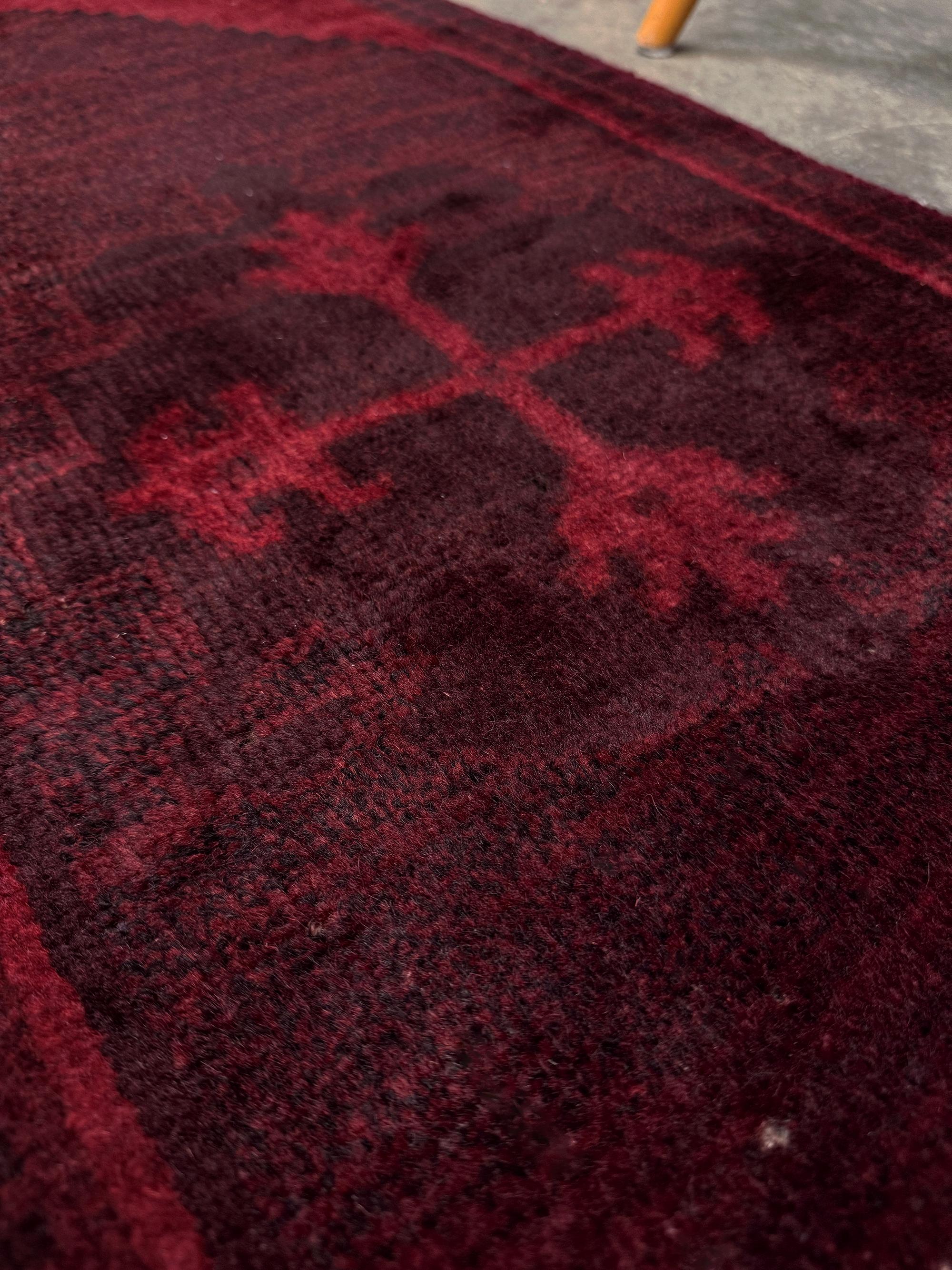 This vintage Turkish mini rug features a powerful ruby-red palette washed with layers of garnet, oxblood, and deep merlot, giving the rug a dramatic, moody richness. The overdyed finish softens the original tribal elements into subtle shadowed