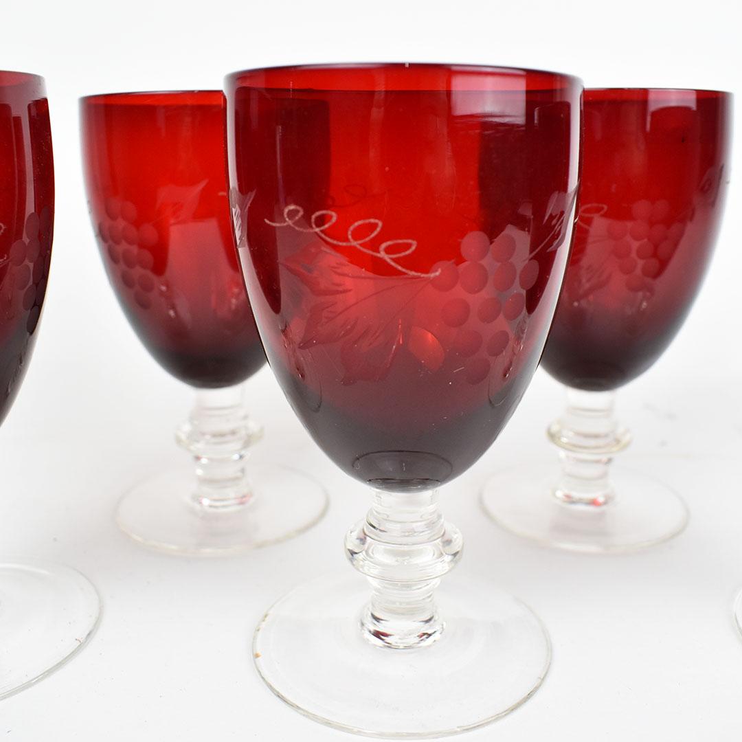 Elegant set of ruby red etched goblet glasses. This set would be fantastic for use as water, wine or ice tea glasses. The base of each glass is red with the surrounding etching of grapes, curling vines and leaves. The stems are clear and short and