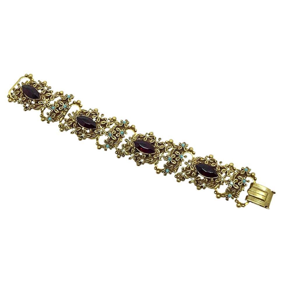 This is a ruby red naiveté rhinestones bracelet. This 1930-40s antiqued brass book link bracelet with fold-over clasp features four large ruby red naiveté rhinestones surrounded with seed pearls and small turquoise bead flowers.

Any additional