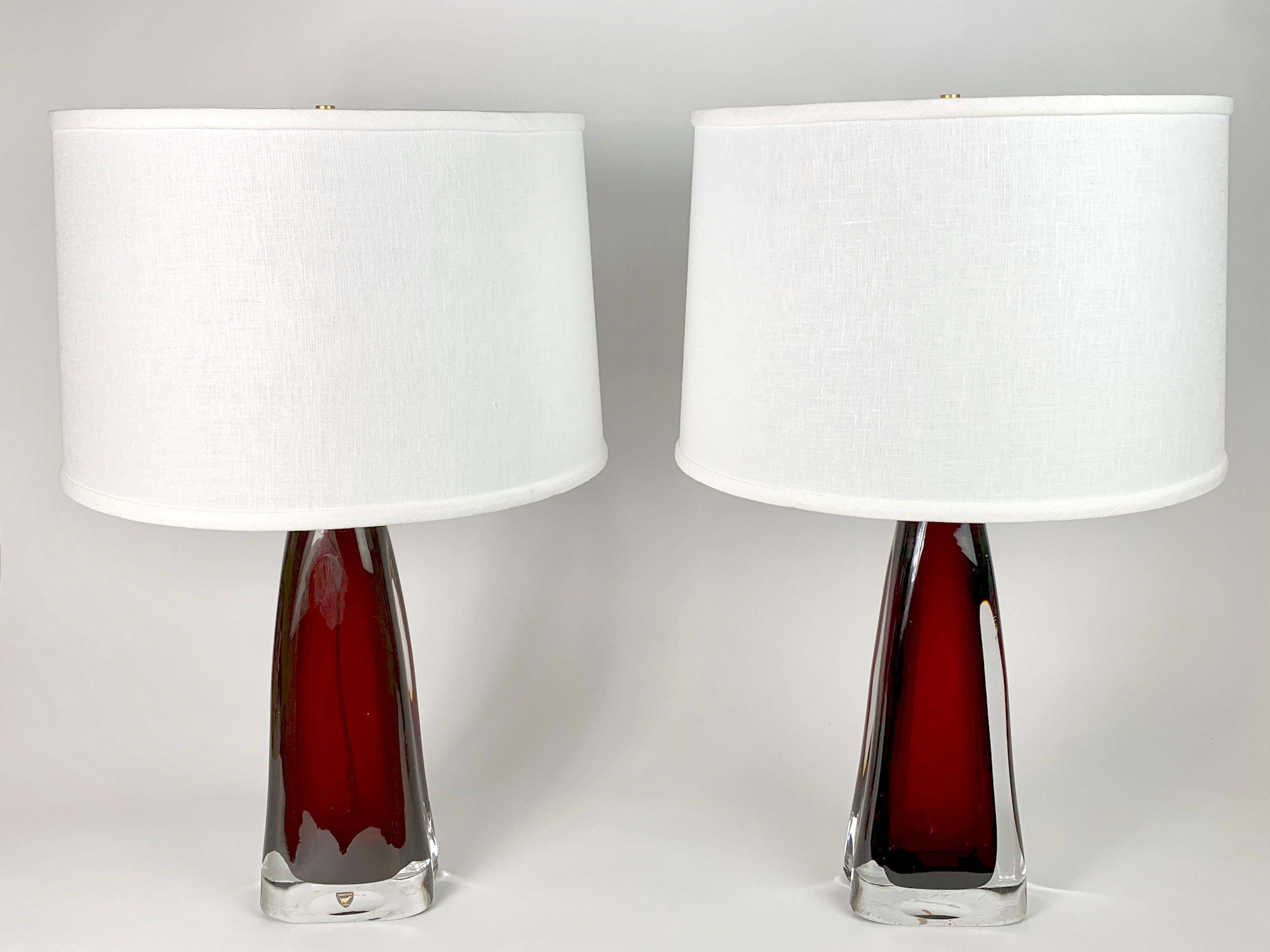 Paire de lampes signées Orrefors en verre rouge rubis avec armatures en laiton conçues par Carl Fagerlund, verre rouge encastré dans une épaisse couche de verre transparent.
Recâblé.

Les abat-jour ne sont pas inclus.