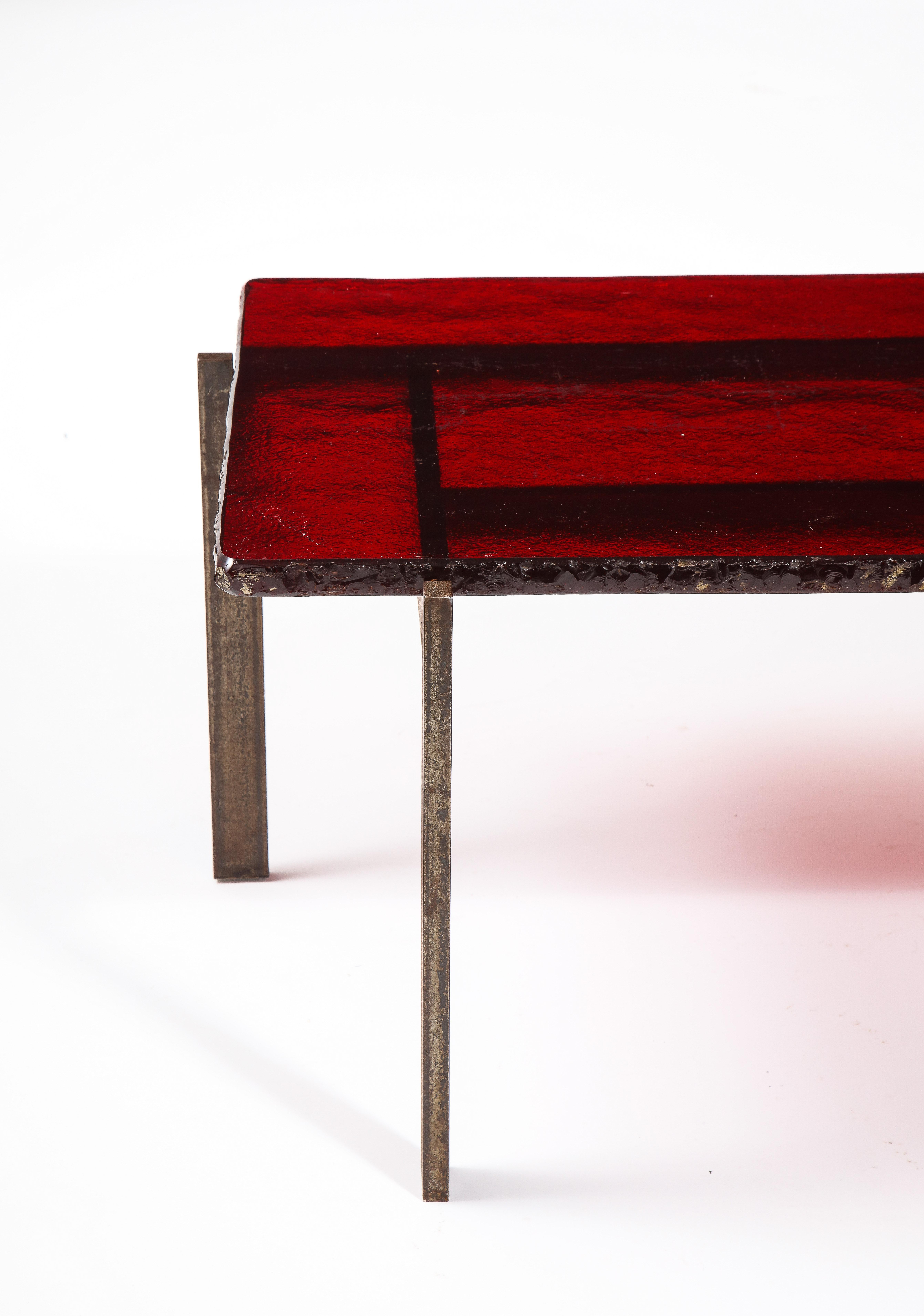 A Spectacular coffee table in cut steel with a ruby red Saint Gobain glass top, the edge of the glass was chiseled then polished to obtain this rough yet consistent finish.