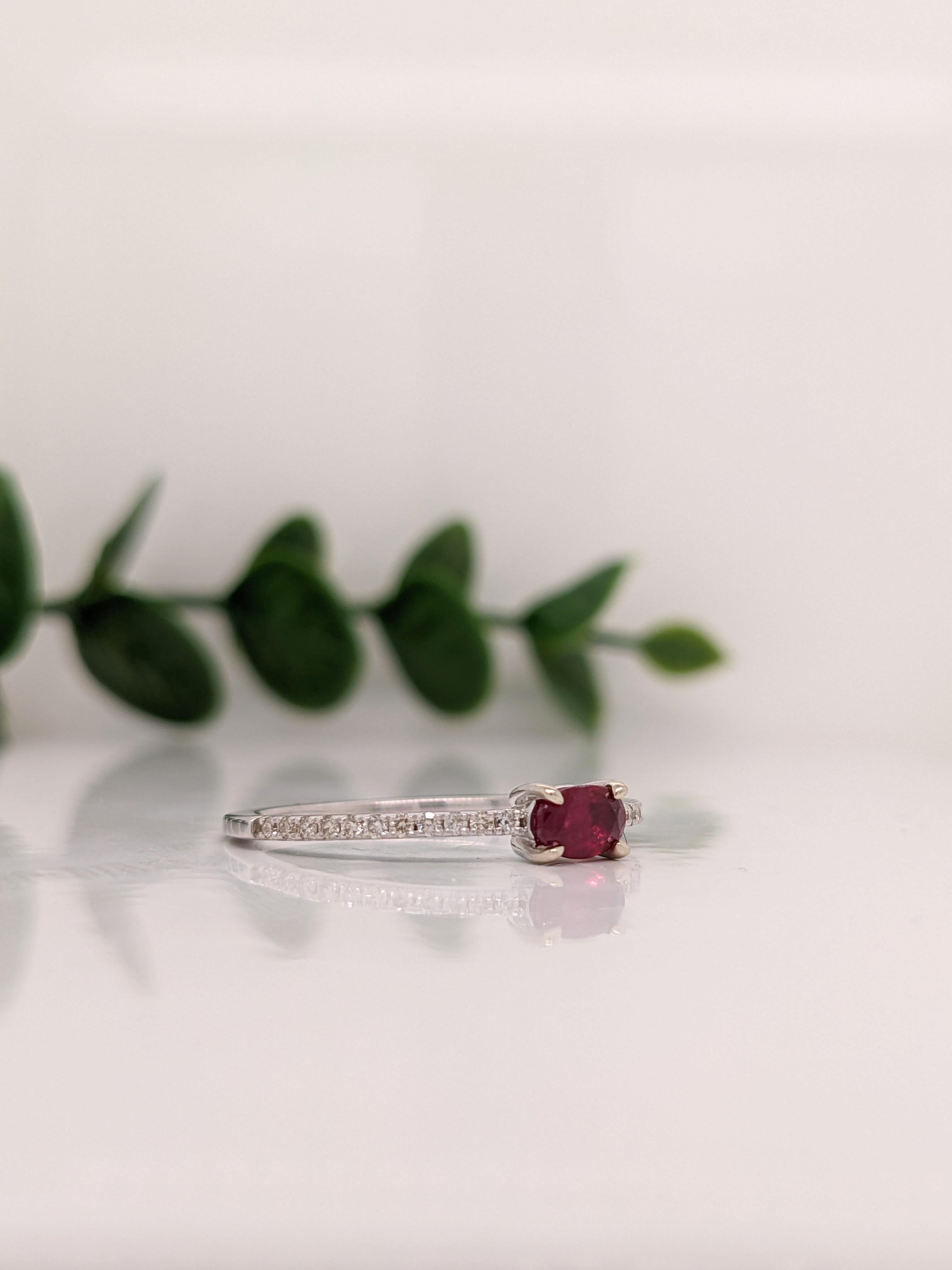This beautiful ring features a sparkling east west prong set red ruby in 14k white gold with natural diamond accents. A delicate ring design perfect for an eye catching engagement or anniversary. This ring also makes a beautiful birthstone ring for