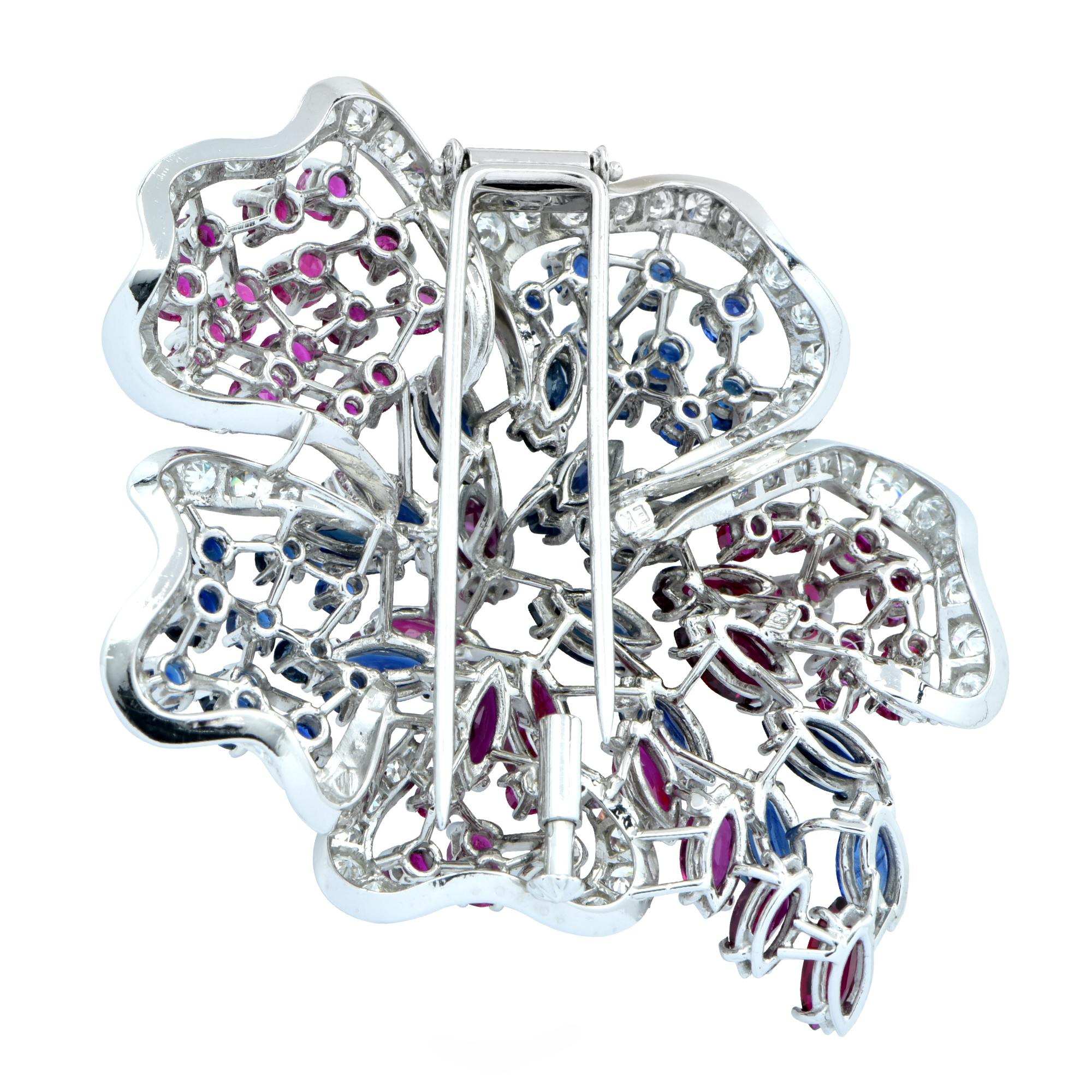 18k white gold brooch featuring approximately 3cts of round brilliant cut diamonds F color VS clarity. Accented by approximately 8cts of rubies and sapphires. This statement piece measures 2.2 inches by 1.8 inches.

Our pieces are all accompanied by