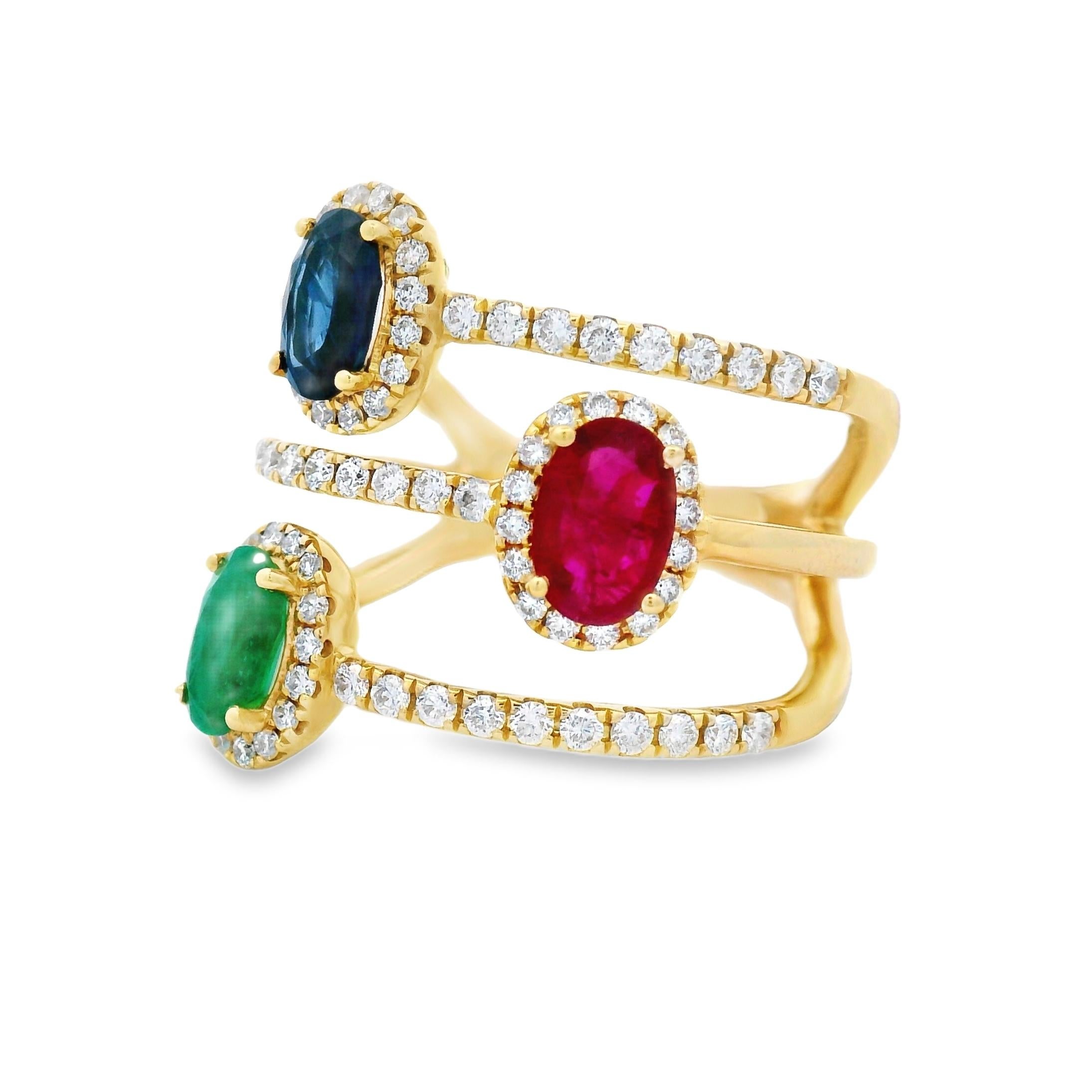 Questo vibrante anello a tre pietre presenta un trio di gemme dal taglio ovale dalle tonalità intense - rubino, zaffiro e smeraldo - ciascuna racchiusa in una raffinata cornice di diamanti e incastonata in una tripla fascia in oro giallo 14K. Con