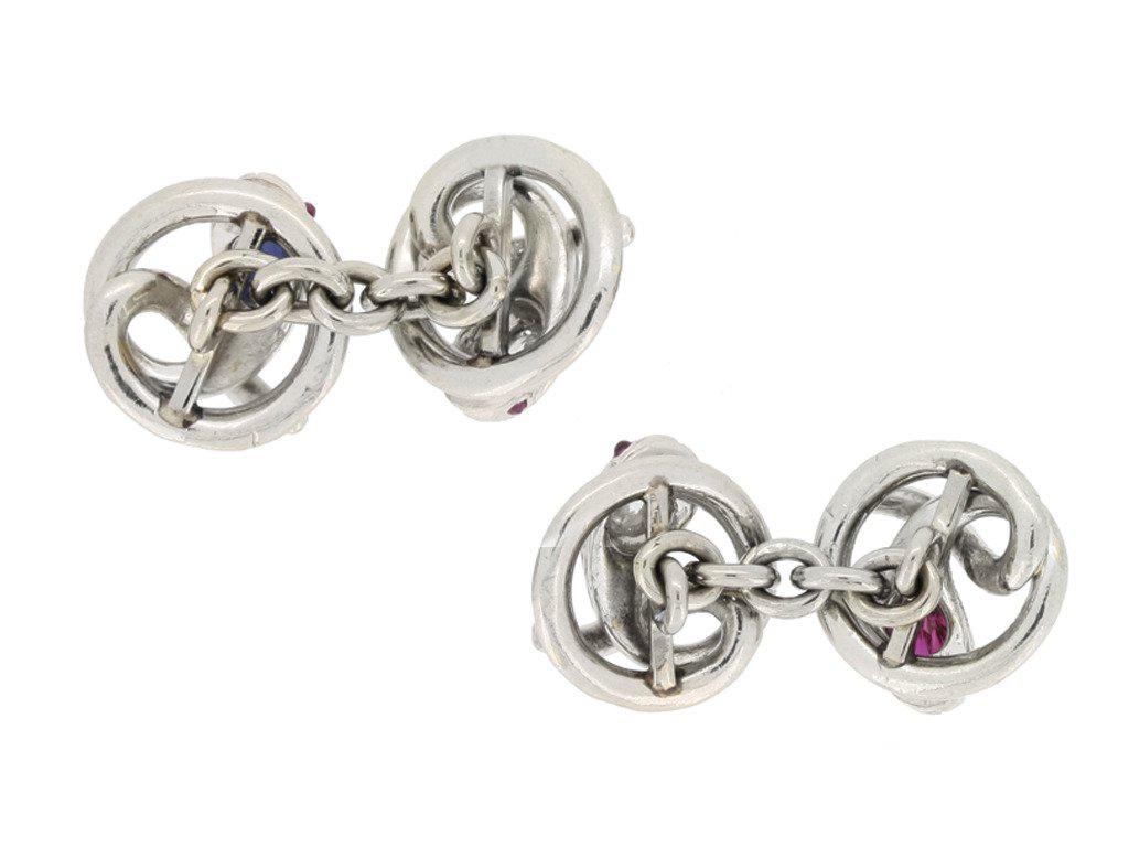 Ruby, sapphire and diamond set snake cufflinks. A matching double sided pair, composed of two twisted circular openwork snake motifs, one pair set with a cushion shape old cut natural unenhanced ruby in an open back collet setting with an