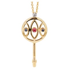 Collier pendentif clé stylisée en or jaune 18 carats, rubis, saphir et diamant