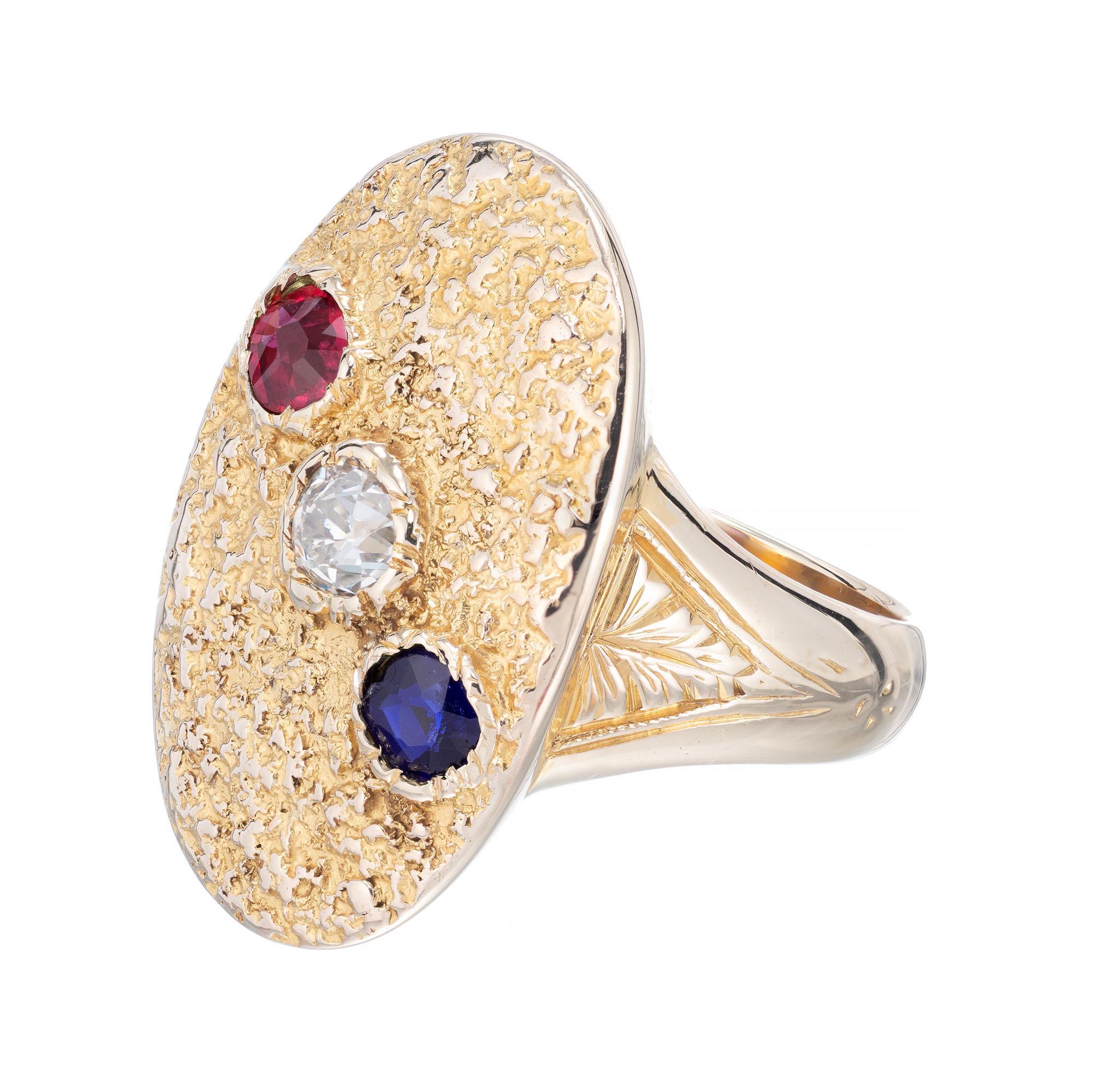 Victorian handmade late 1800's to early 1900’s signet style pinkie ring with textured top set with one round ruby, round diamond and a round sapphire, in a 14k yellow gold setting. 

1 old European cut diamond, approx. total weight .20cts, H, SI1
1